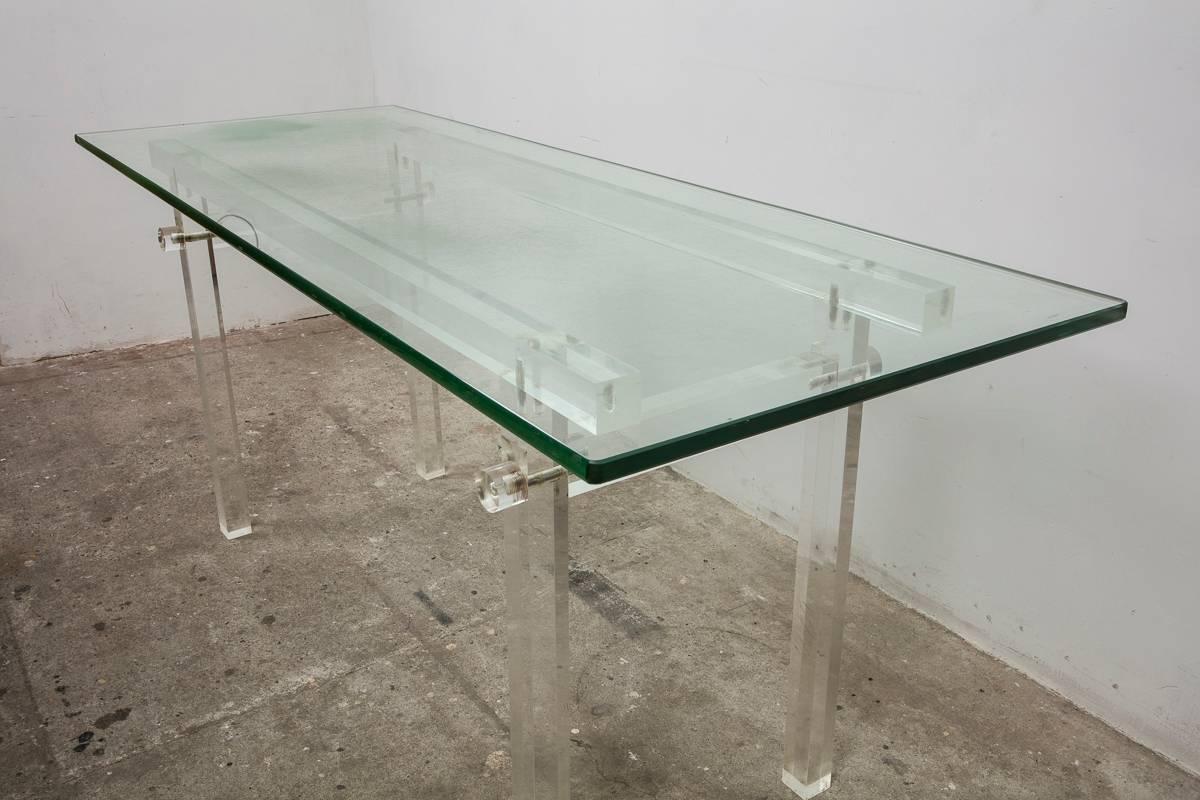 Beautiful 1970s clear acrylic dining table, console with thick glass top designed in a square Lucite frame connected with Lucite screws

The glass top has traces of use.


   