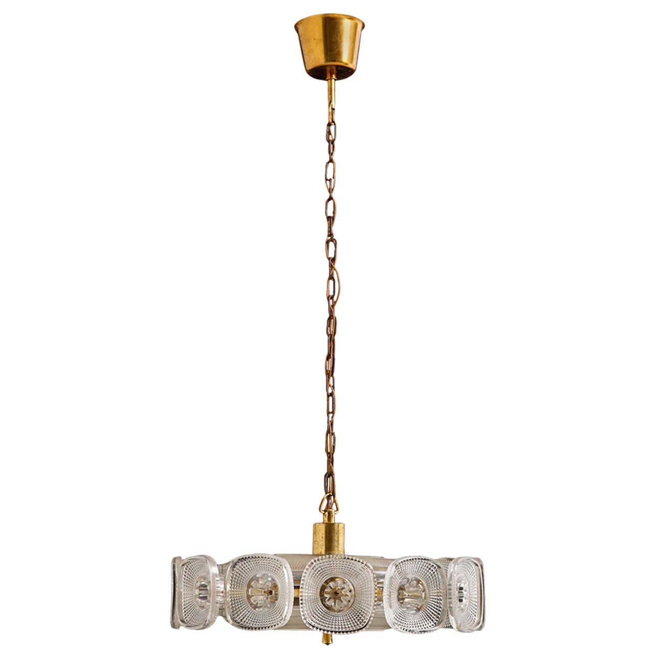 Rare pendant light in brass and thick glass by Carl Fagerlund for Orrefors glass works. A sturdy brass construction with a 3 light bulb socket of e15 size. The brass construction is covered on top and bottom with thick crystal plates and twelve cup