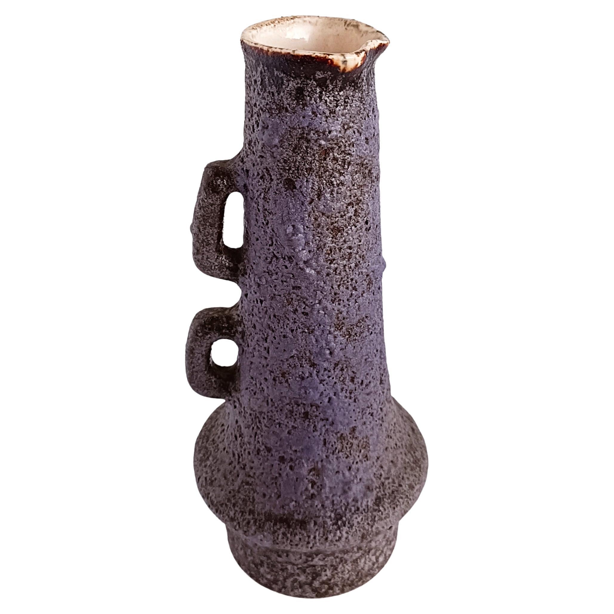A beautiful ceramic jug featuring the lilac color Fata Lava glazing so characteristic of the Vest Ceramic studio production circa the 1960s. Marius Van Woerden focused on this type of brutalist ceramics, creating organic shapes and raw fat lava
