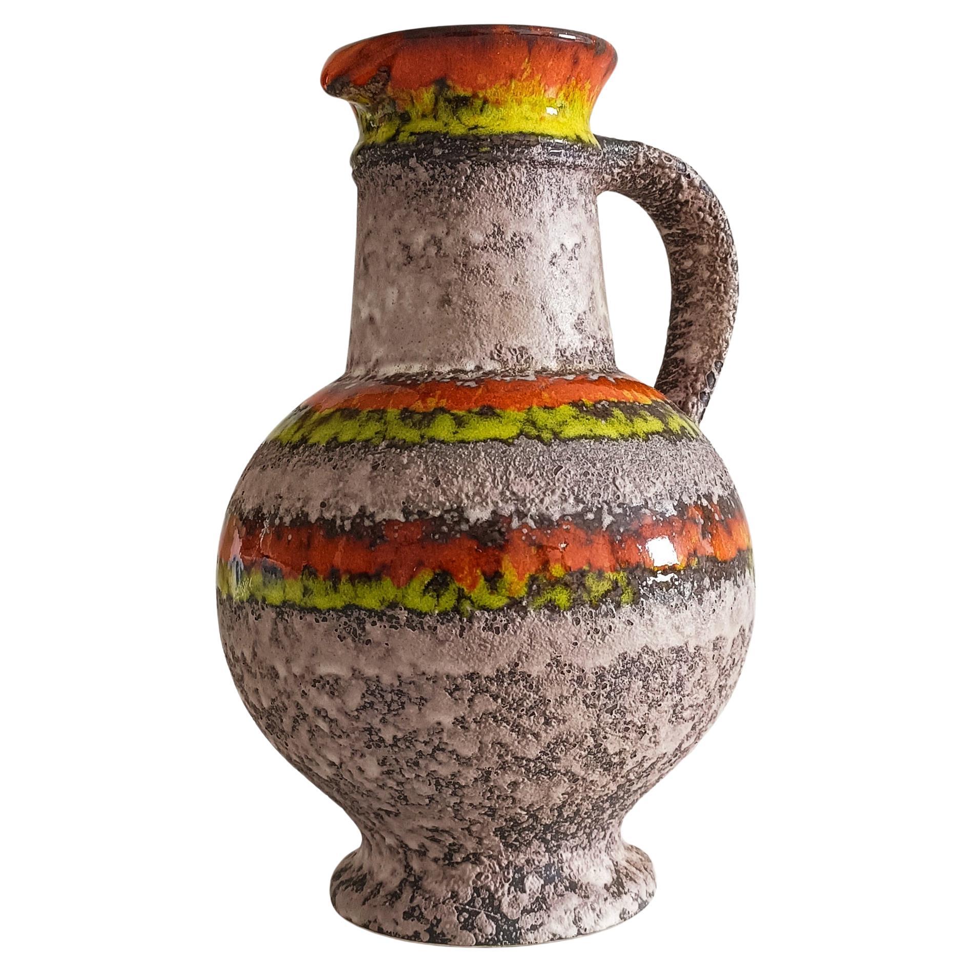 This striking Fat Lava pitcher, designed by Heinz Hommerich for Übelacker or Ü Kermik, embodies the bold and organic aesthetic of mid-century West German ceramics. 

The pitcher’s surface features the distinctive rough volcanic texture of the Fat