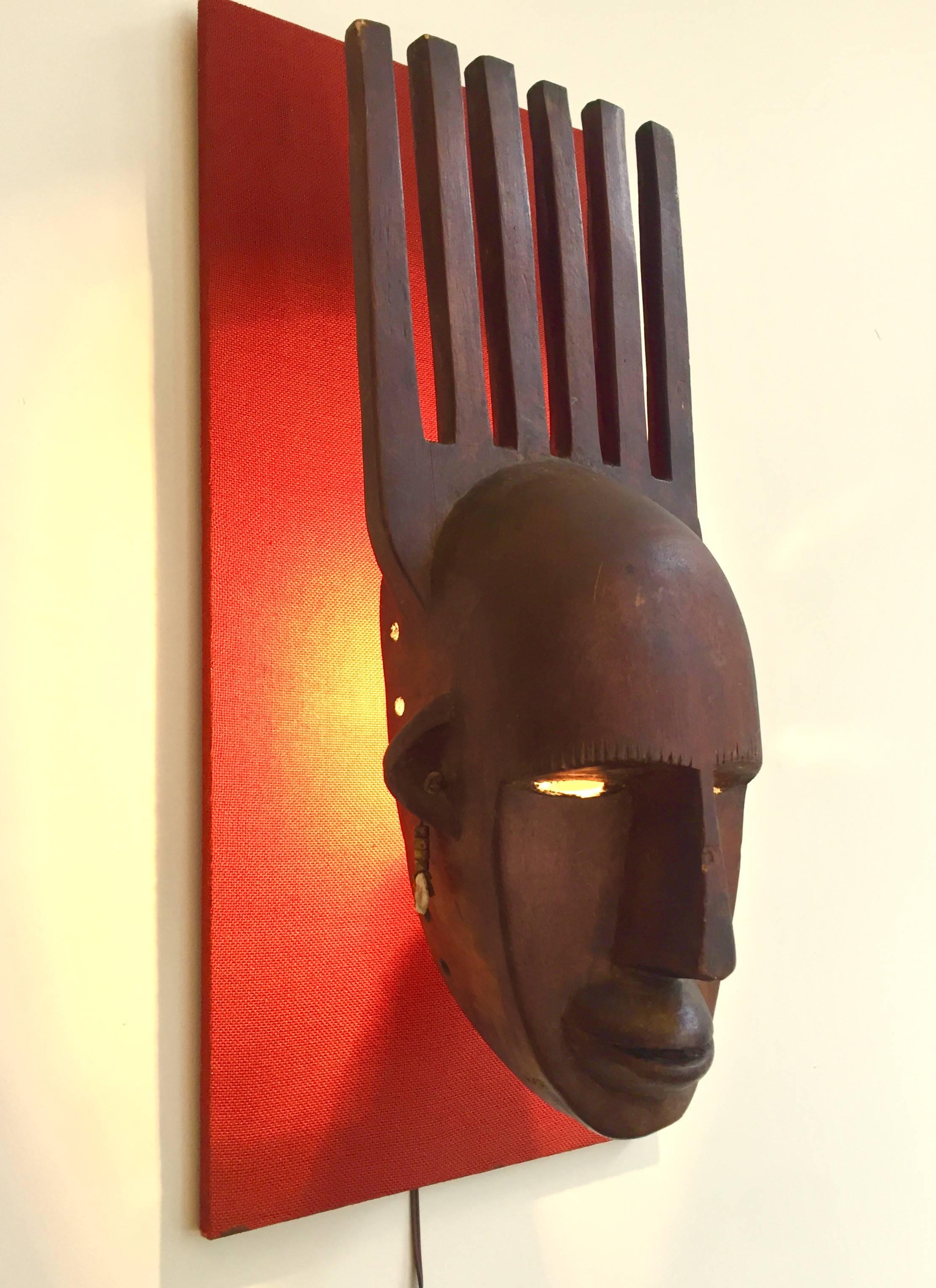 African (Mali) mask mounted on wooden panel with integrated light.