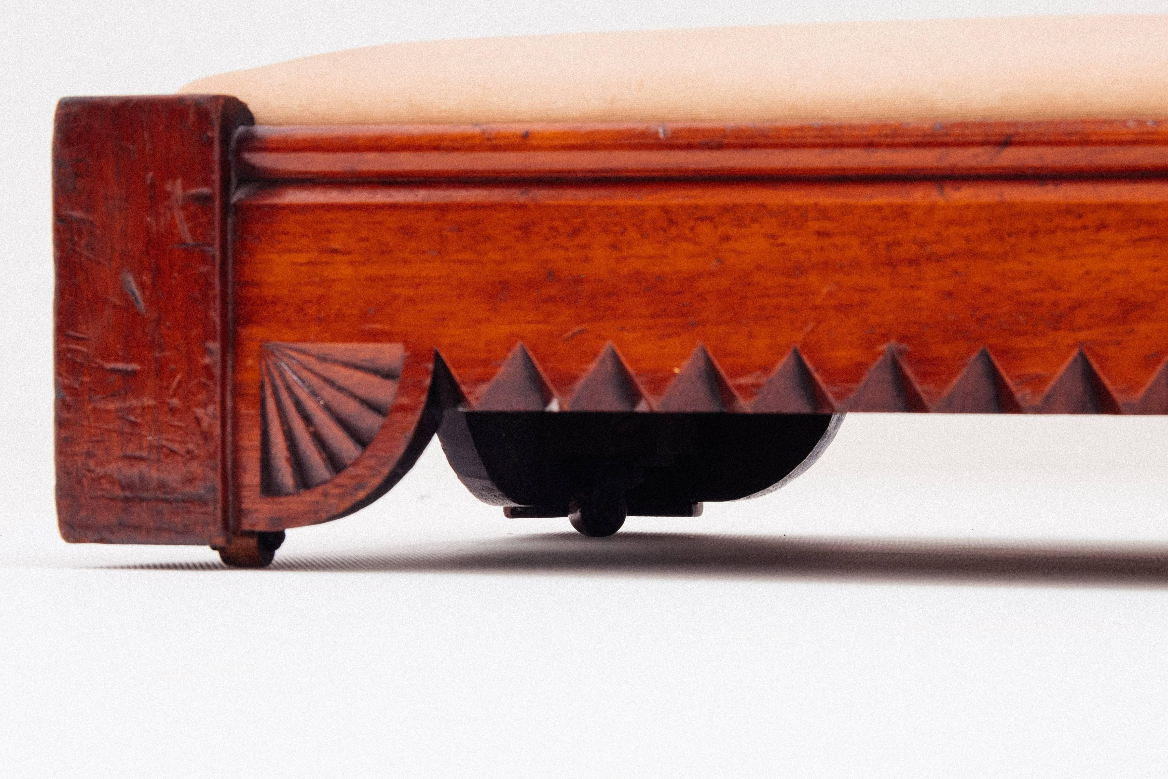 Very handsome and elegant low bench. Beneath you find hand-carved wooden wheels to roll it from beneath a sofa or bed.
 