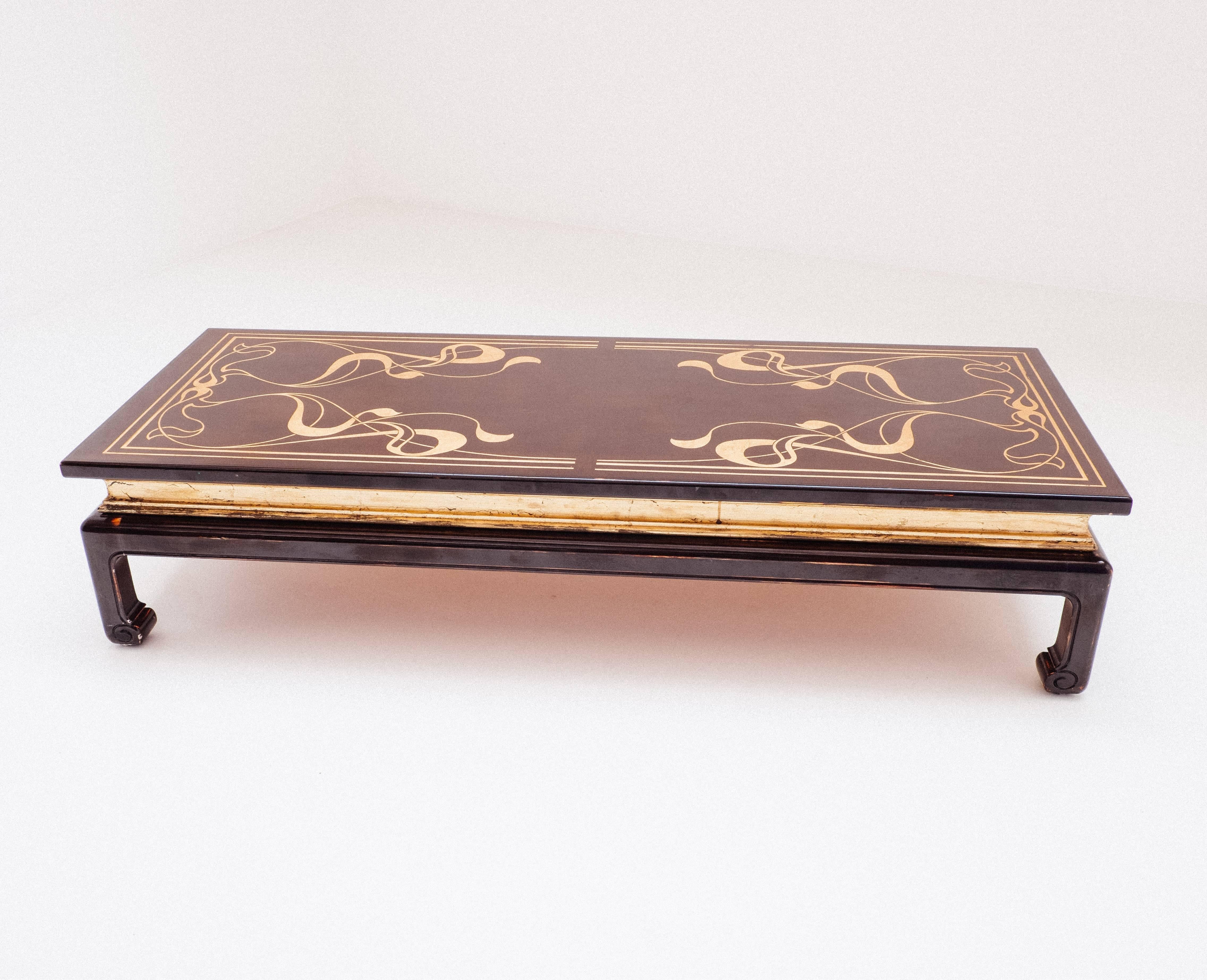 Very decorative chocolate brown coffee table with a golden oriental / Art Nouveau design on the surface.