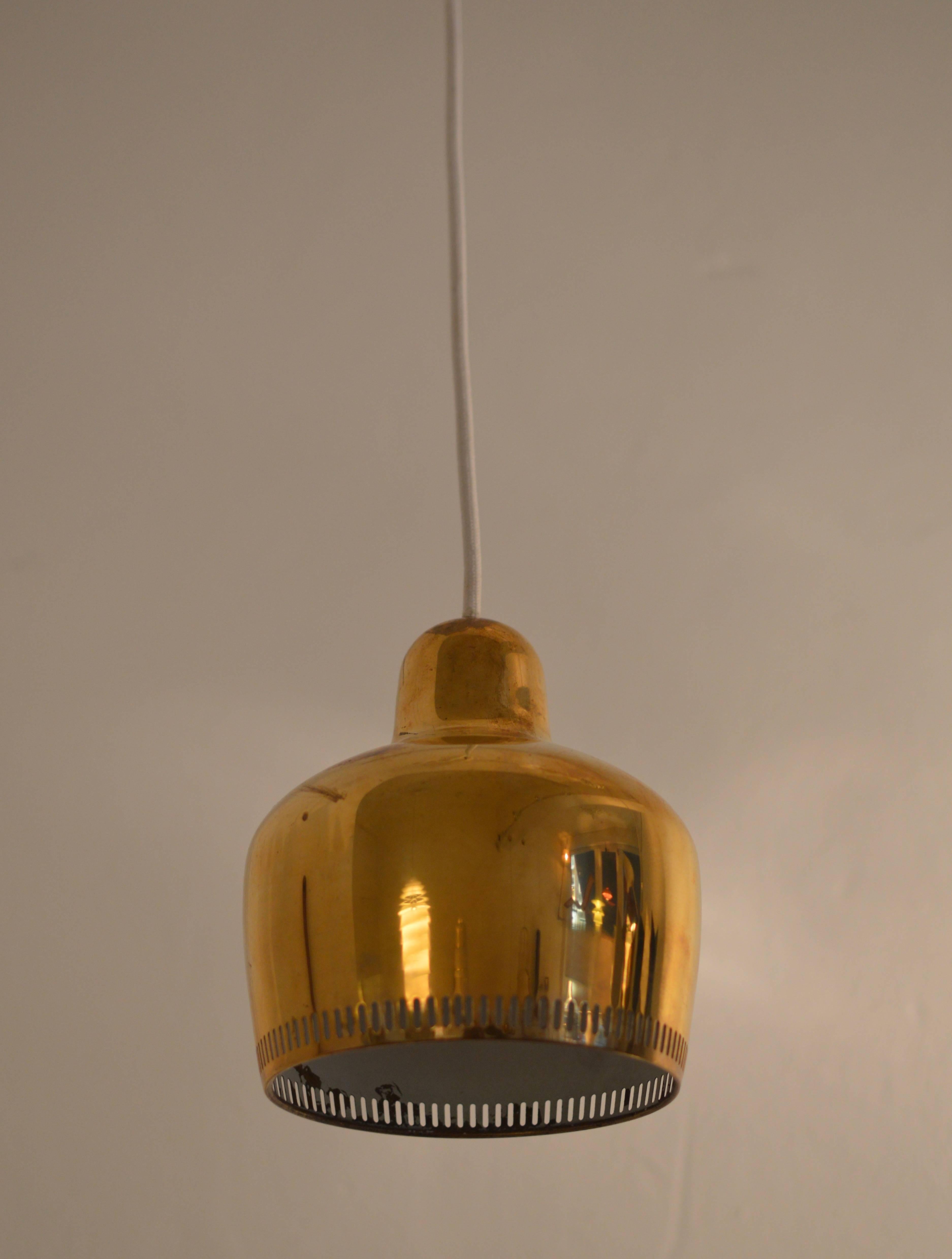 In 1936 Aino and Alvar Aalto were commissioned to design the interior of the Savoy Restaurant in Helsinki for which they designed this 'Golden Bell' pendant made out of one brass sheet of steel. The die cut stripe pattern perforated rim provides a