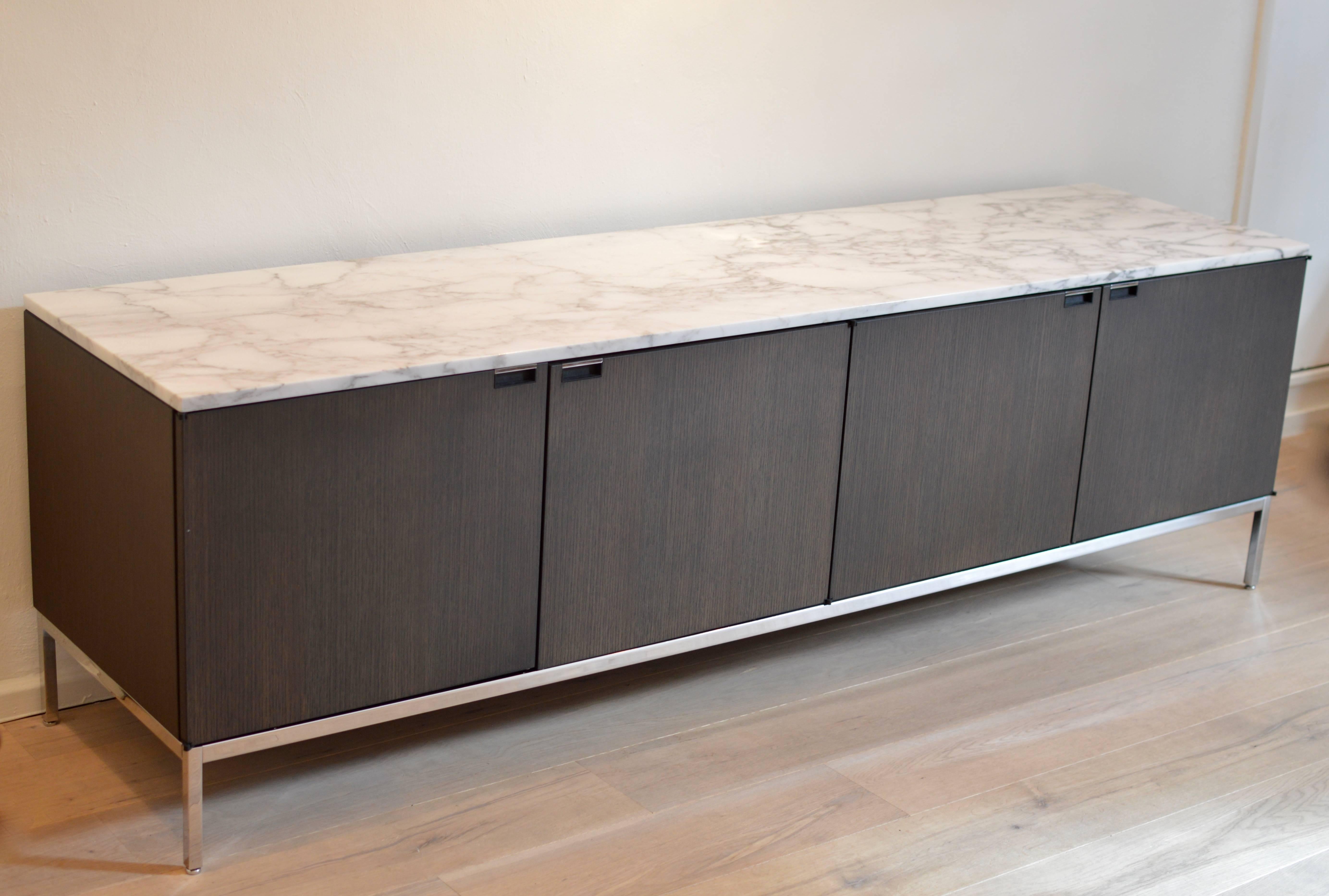 Fully equipped four drawer credenza by Florence Knoll with marble top executed in grey stained oak on chrome base with Arabescato (white with grey veining) marble-top.
Left compartment comes with two large shelves (half the size of the credenza),