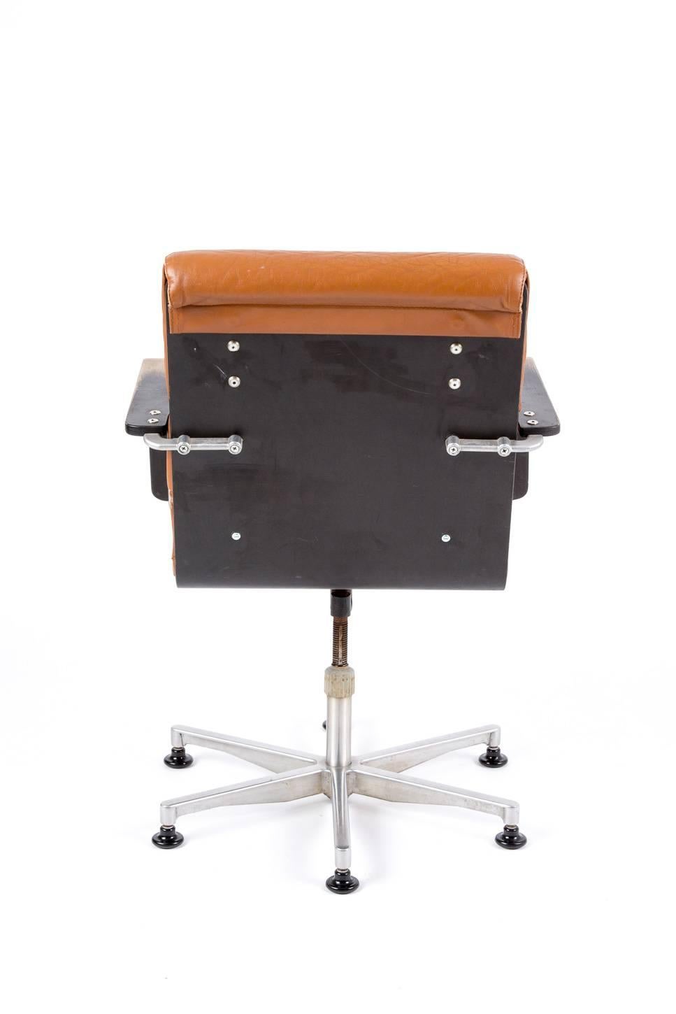 Office chair of Yrjo Kukkapuro. This chair is constructed with the most nice details in plywood and aluminium. Also the leather sitting has the perfect form. Swivel and turn around. Brown cognac leather. Armlegs are black.