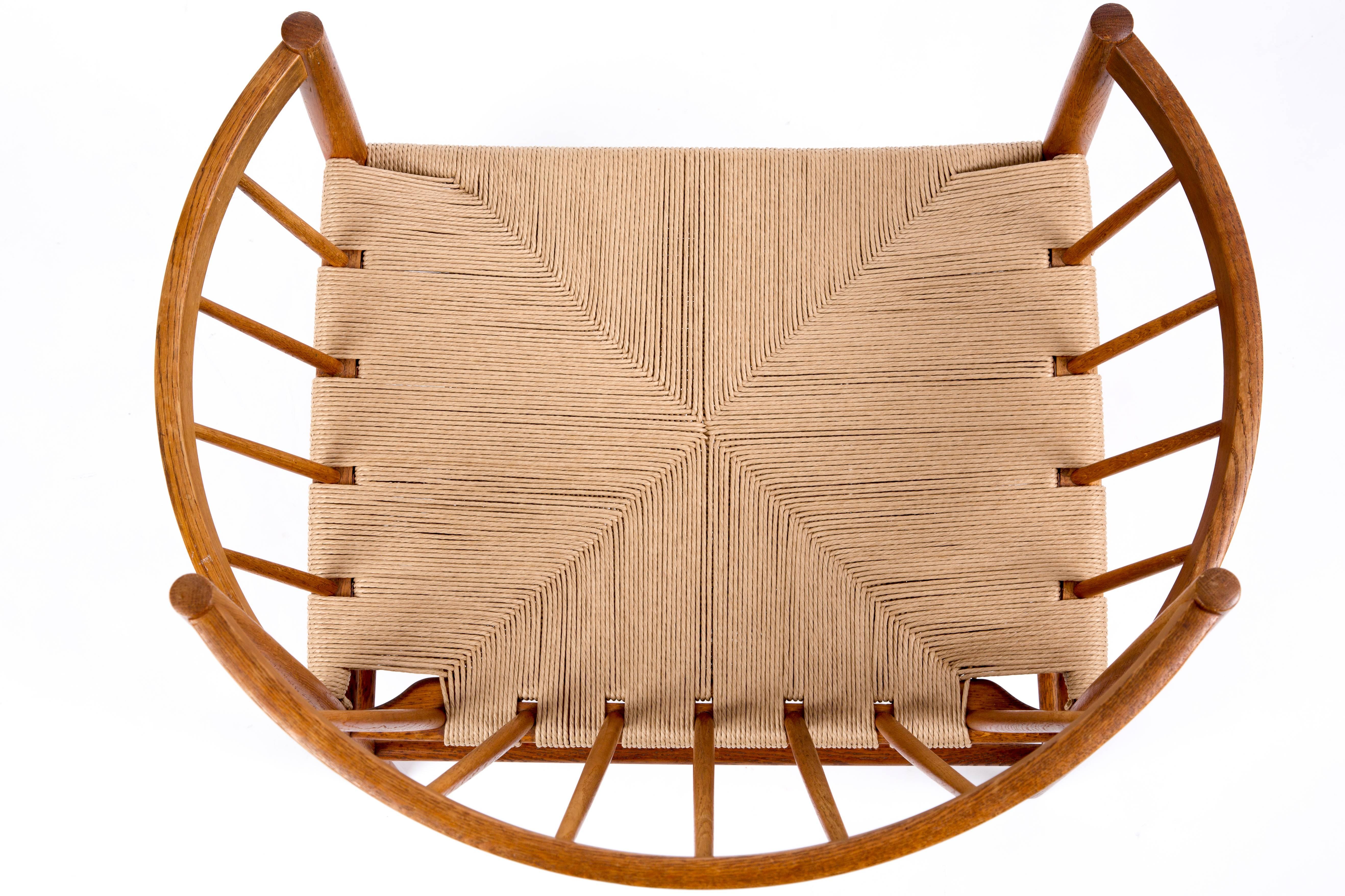 Jorgen Baekmark, the design of this chair is nearly a circle, seen from above. The back and the armrests create a circle together. This is the power of design of the chair. The frame is of warm colored wood. The paper cord is new, so you can sit for