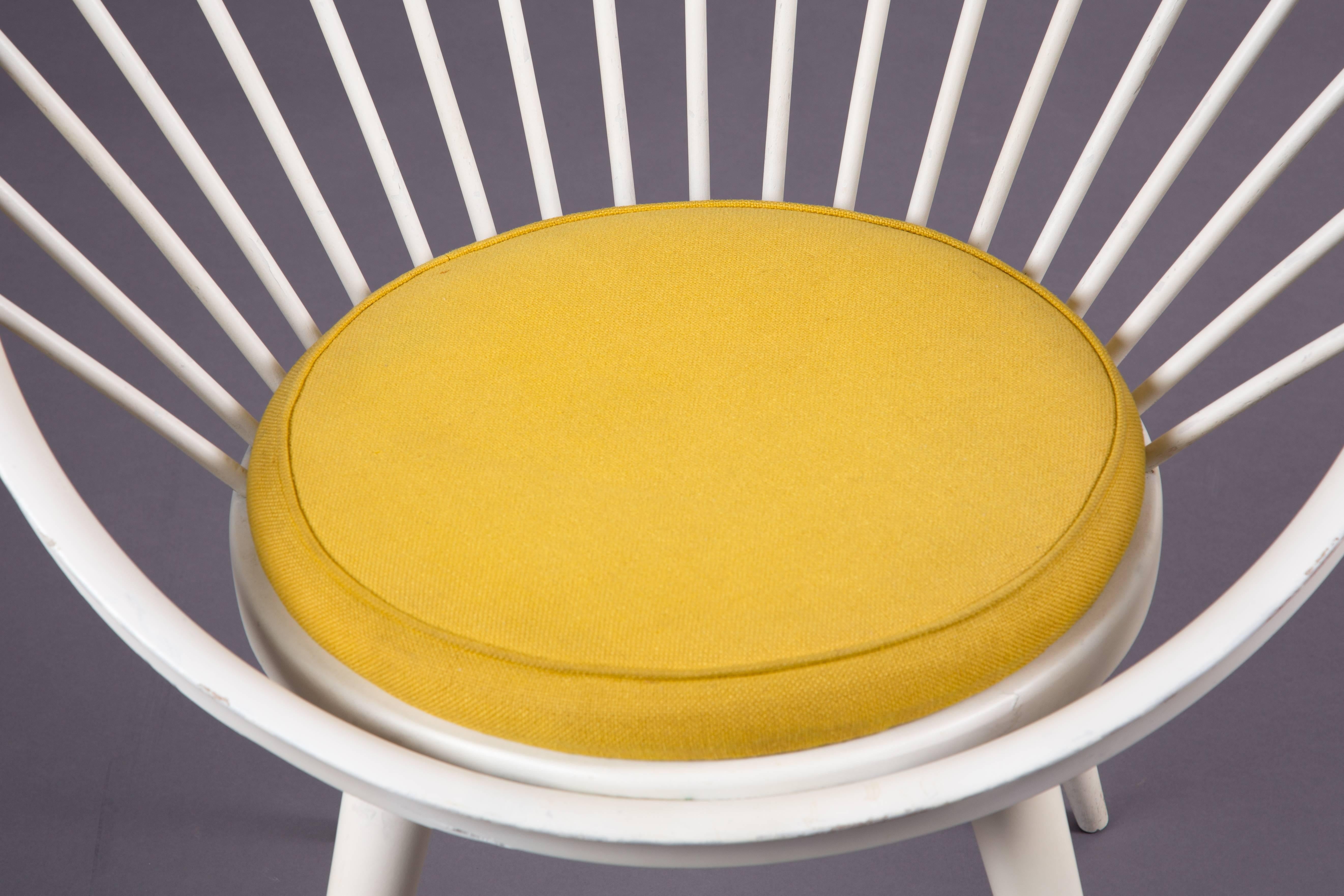 A circle chair designed by Yngve Ekström with a yellow fabric cushion.