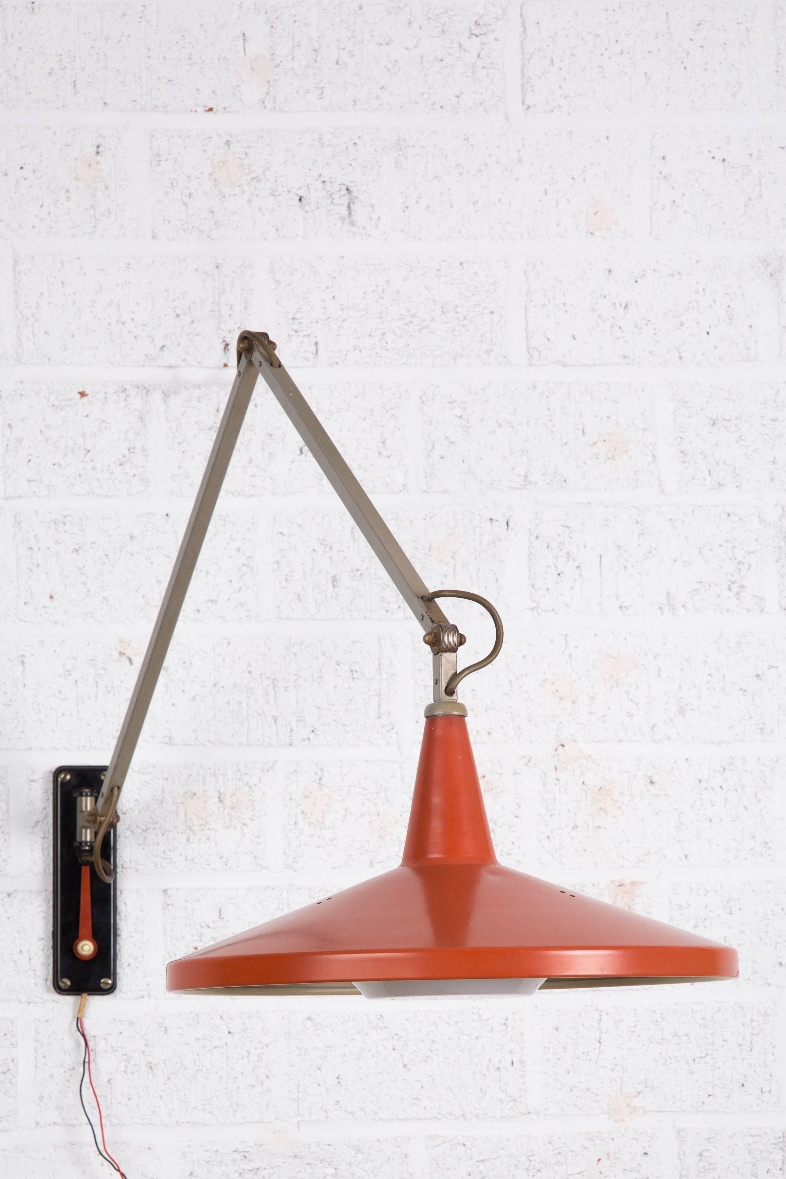 Panama Gispen Rietveld. Diese Gispen Lampe wurde von Wim Rietveld und AR Cordemeijer entworfen. Es handelt sich um eine Wandleuchte. 
Das rote Werkzeug kann verwendet werden, um die Lampe neu zu positionieren.
Die Lampe hat einen neuen