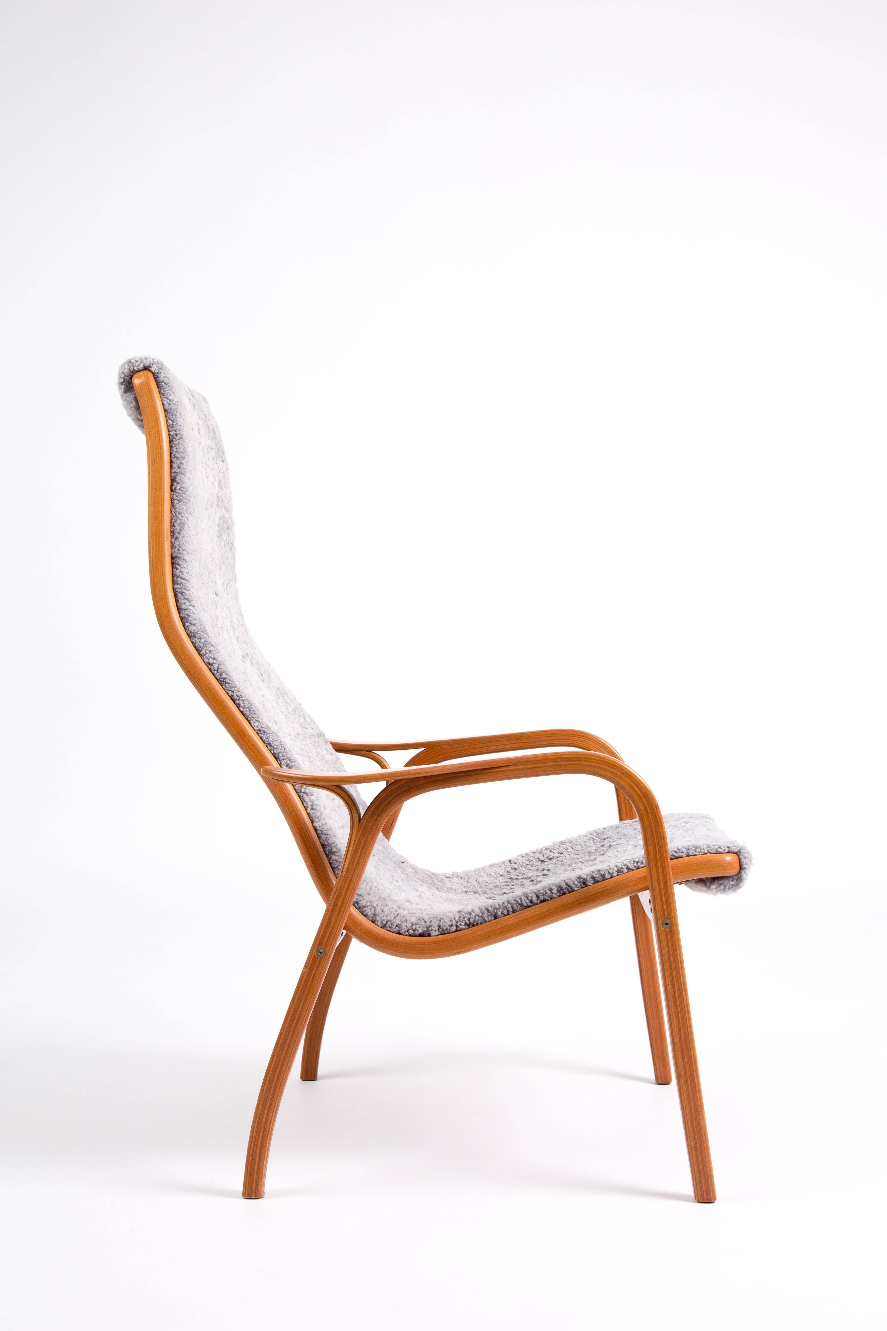 The Lamino chair of Yngve Ekström from Sweden. The laminated wood is of rare cherrywood. The sheepskin has a blue-grey color. The way of building this chair around the armrest is very special. Flowing laminated forms!