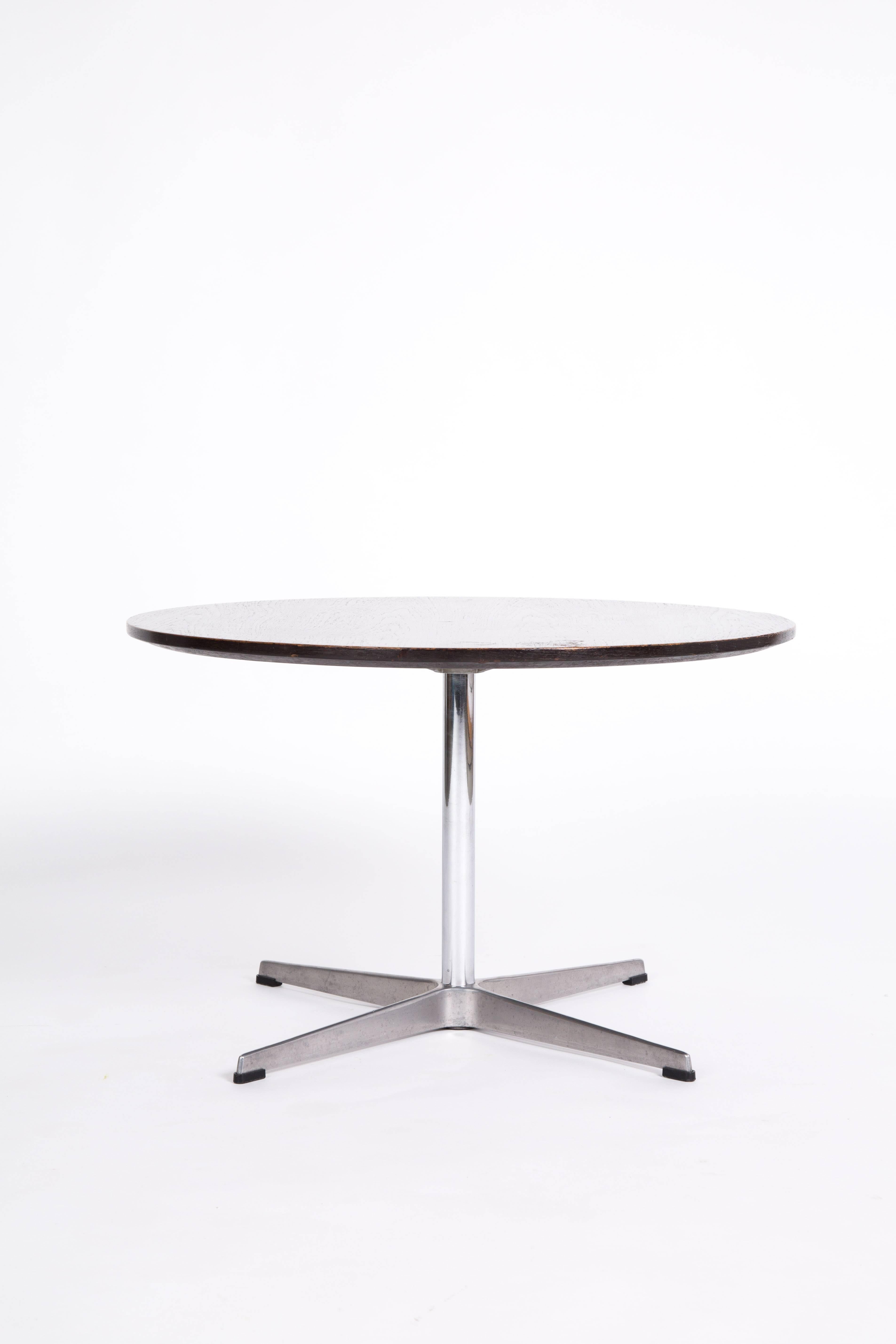 A round coffee table with a darkwood top. The round edge goes from small to thick. So the table looks thin, but the construction is stark by its thick centre. Very nice alumium base.