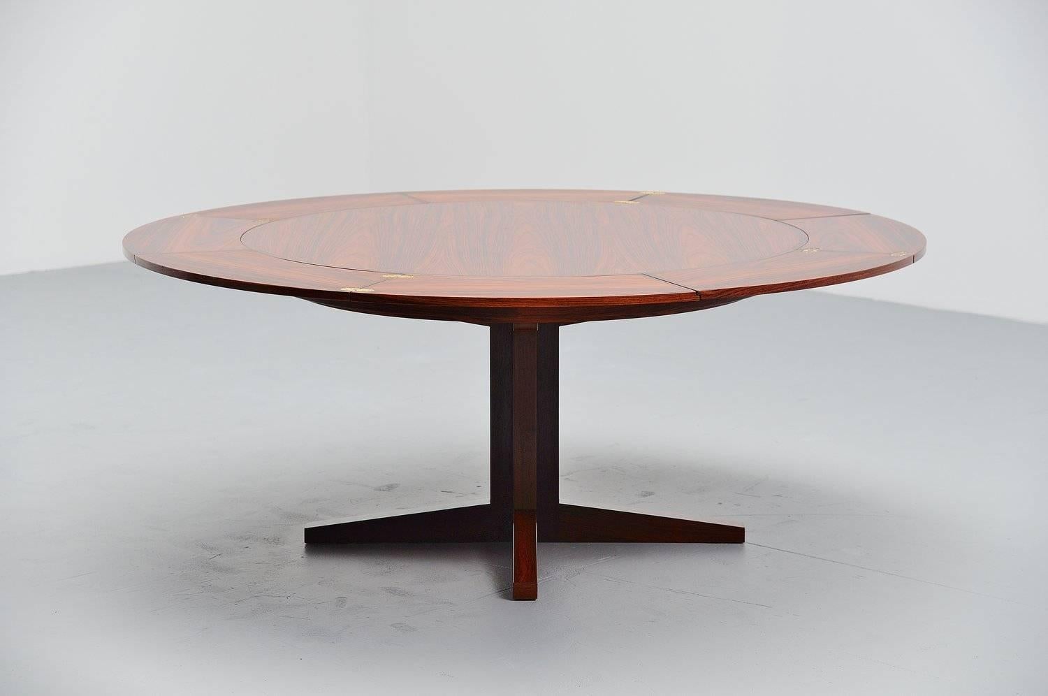 Spectacular rosewood dining table designed and manufactured by Dyrlund, Denmark, 1962. This amazing round table has a star-shaped base and can be extended by extracting the 4 2-pieced extraction leafs that are stored underneath the top. The width in