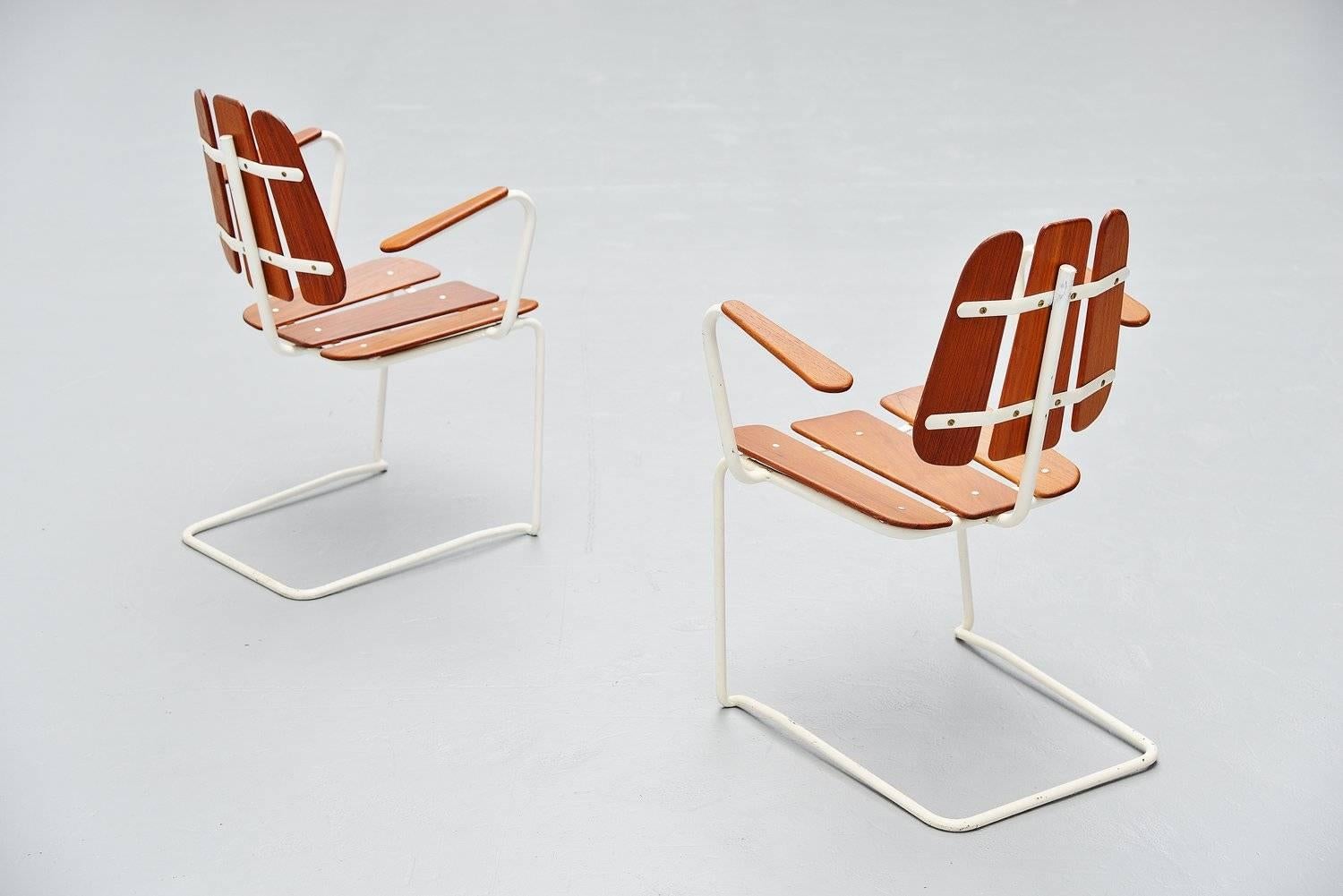 Very unusual pair of cantilevered garden chairs made in Sweden, 1960. These chairs have an off white lacquered tubular metal frame. The seats and backs are made of solid teak wooden slats. The chairs are in very good original condition and were