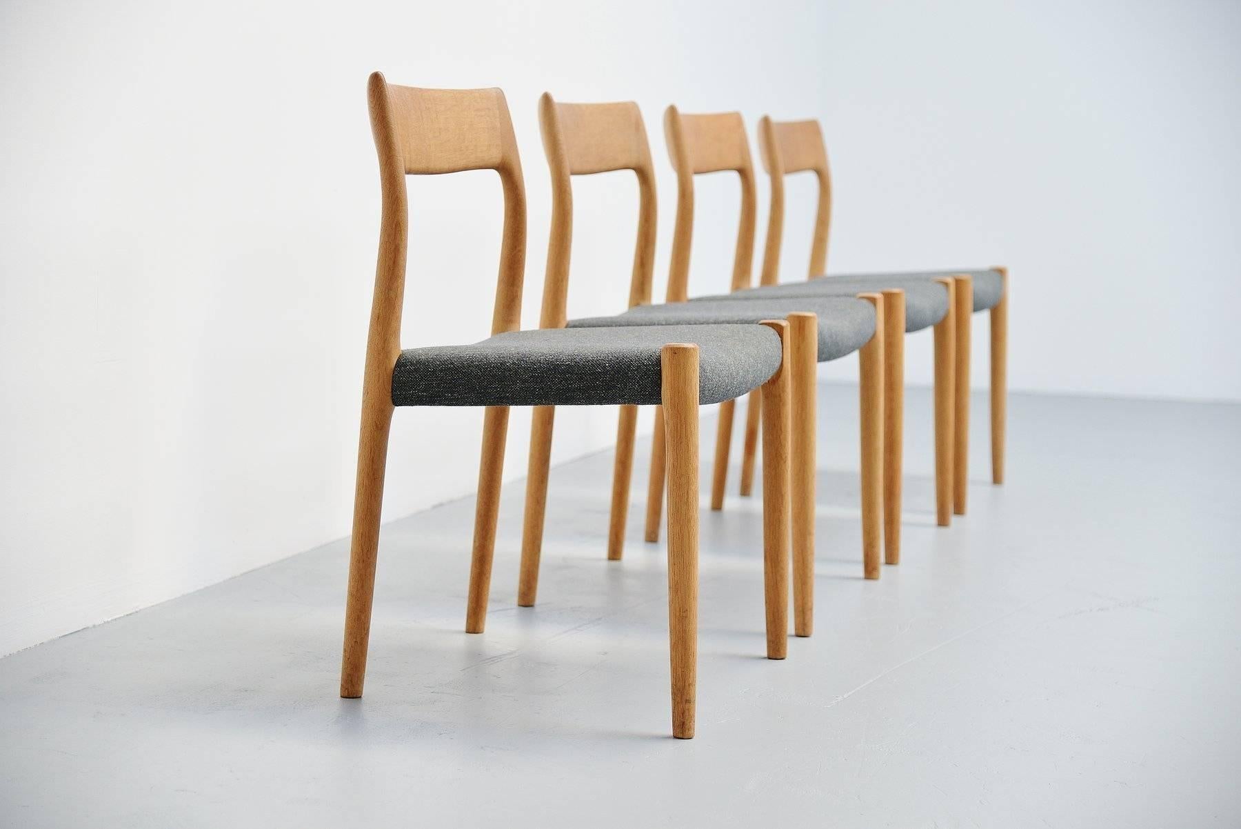 Very nice set of four dining chairs model 77 designed by Niels Moller for J.L. Møller Mobelfabrik, Denmark, 1959. These chairs are made of solid oak wood and have new dark grey upholstery that is really nice in contrast with the light oak wooden