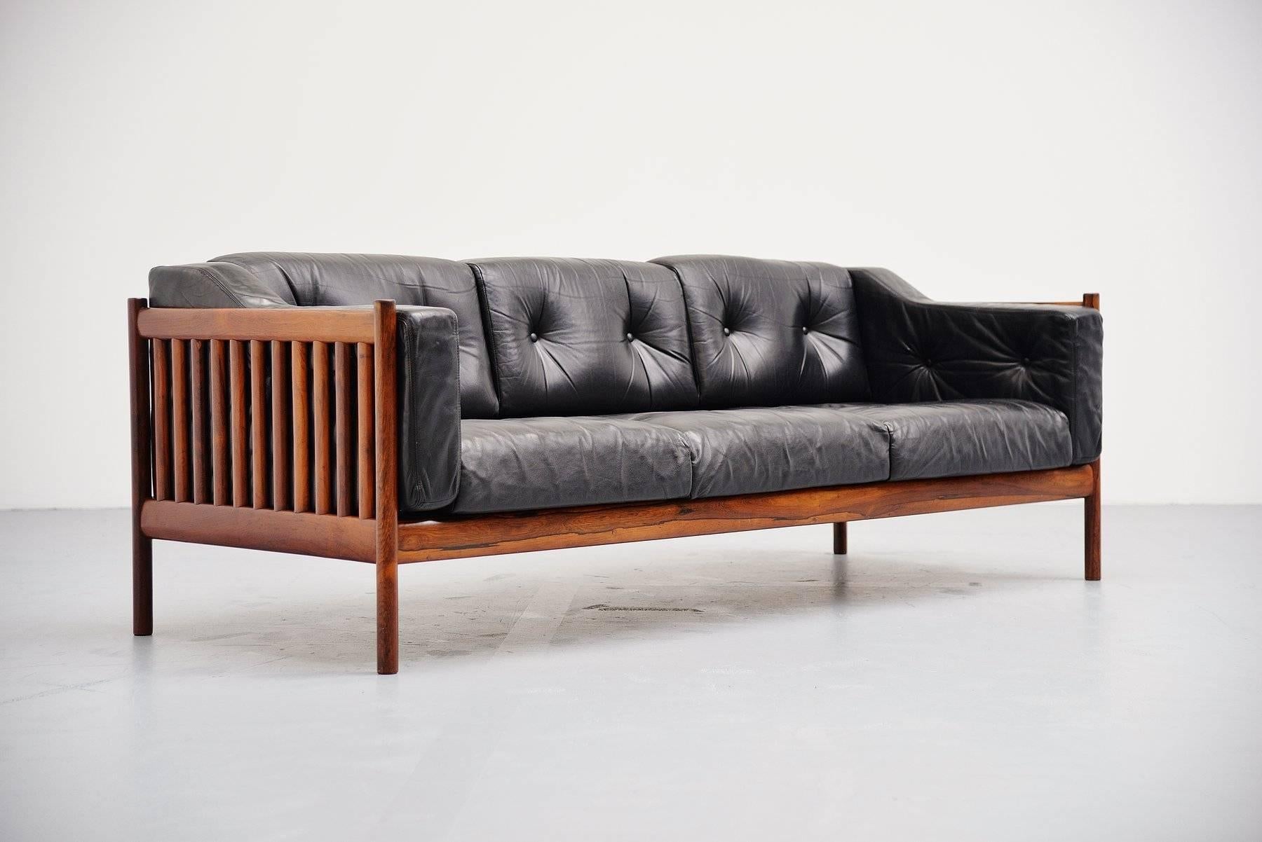 Very nice solid rosewood and black leather lounge sofa made in Denmark, 1960. This sofa has a solid rosewood frame with rosewood spines all round which looks very nice in contrast with the black leather. The black leather cushions are made of high