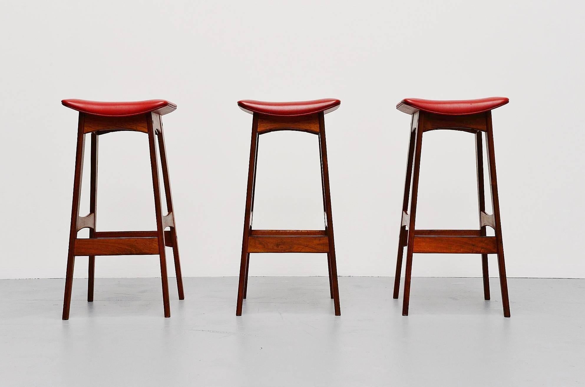Fantastic set of three counter bar stools designed by Johannes Andersen manufactured by Brdr. Andersens Møbelfabrik A/S, Denmark, 1961. These stools have a solid teak base with black metal protected feet rest. The stools are originally upholstered