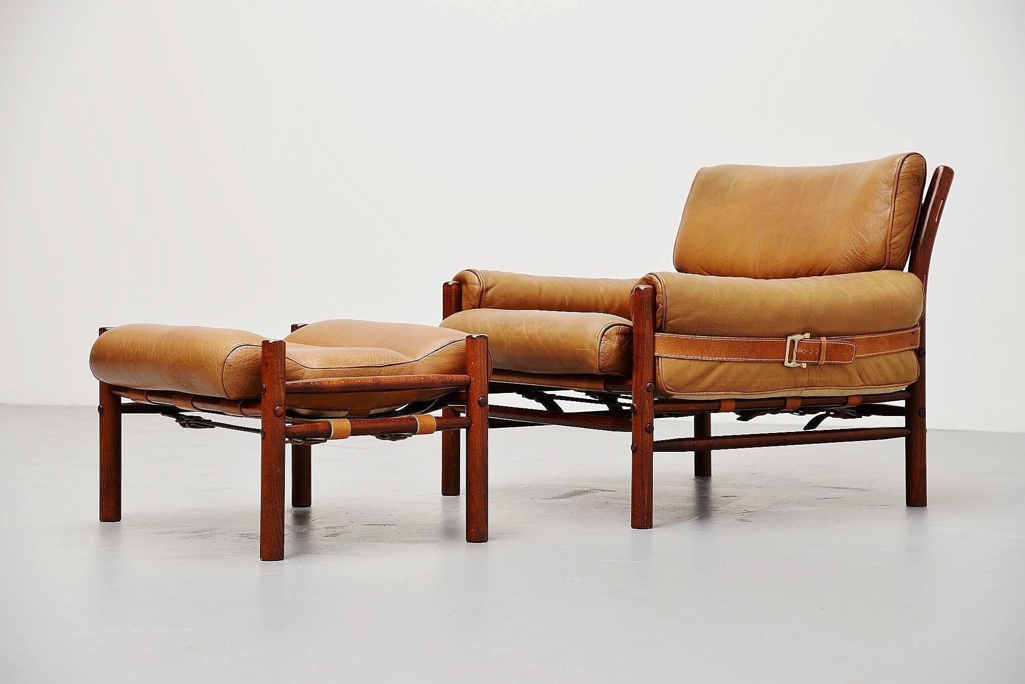 Comfortable leather lounge chair and ottoman designed by Arne Norell, manufactured by Norell AB, Sweden 1960. This has a dark stained beech wooden frame, easy to completely disassemble. The chair is held together by the seat that was strapped with