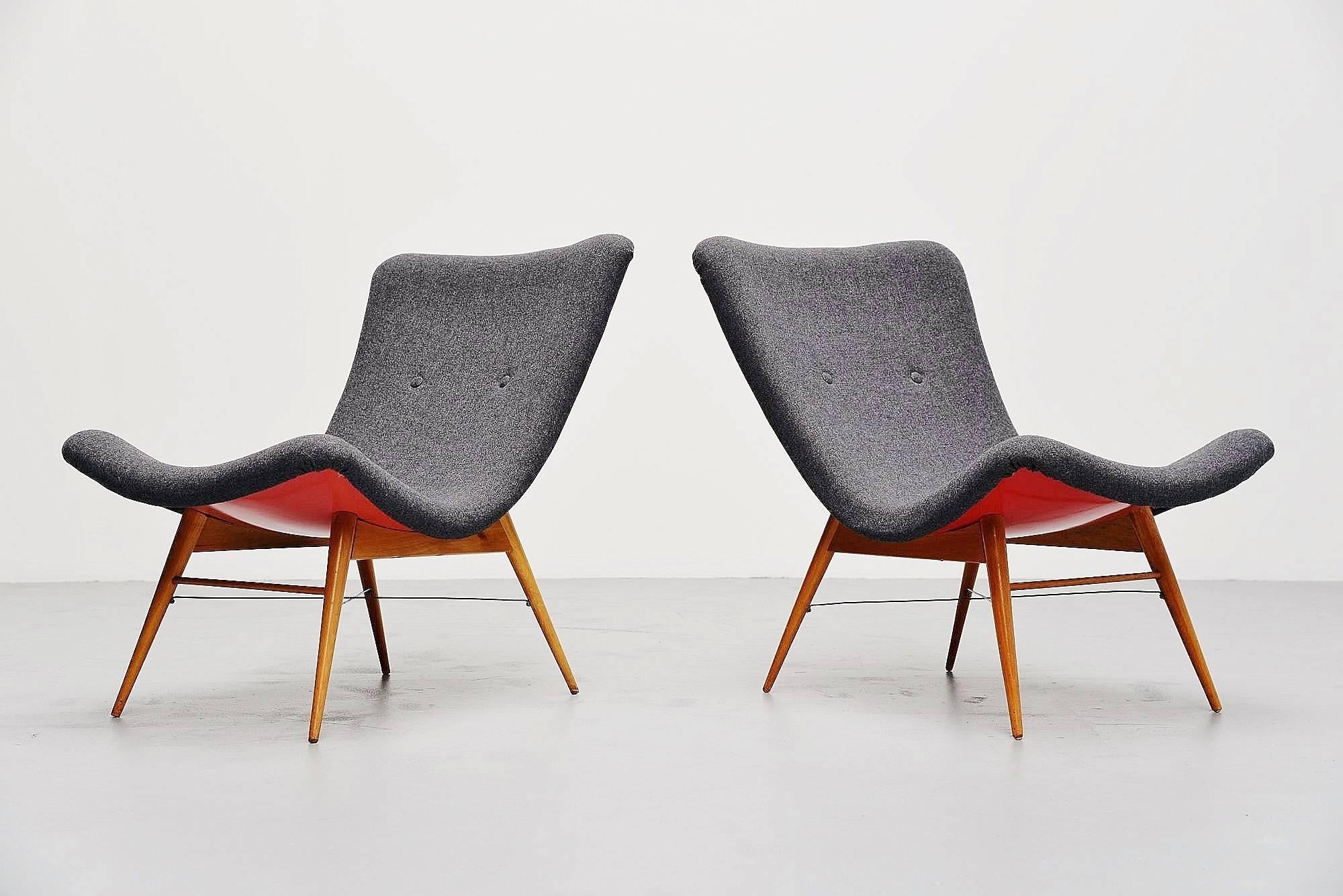 Very nice pair of low lounge chairs designed by Miroslav Navratil, manufactured by Cesky Nabytek, Czech Republic 1959. These chairs are very unusual with birch wooden legs, stabilized with the metal cross connection in between. The shell is made of