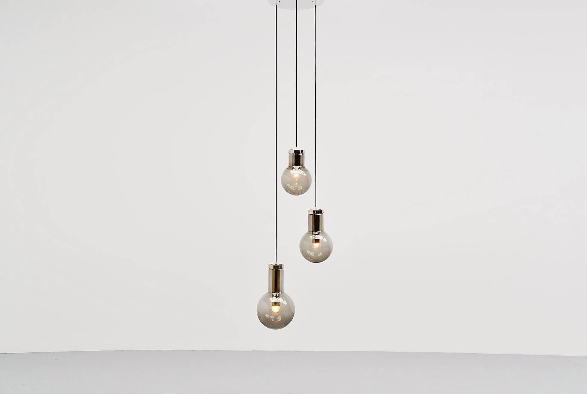 Very nice set of three pendant lamps designed and made by RAAK Amsterdam, Holland, 1965. These lamps are called maxi globes and this is a set of all three different sizes. The lamps have brown fume glass and a brass fixture. We can make two similar