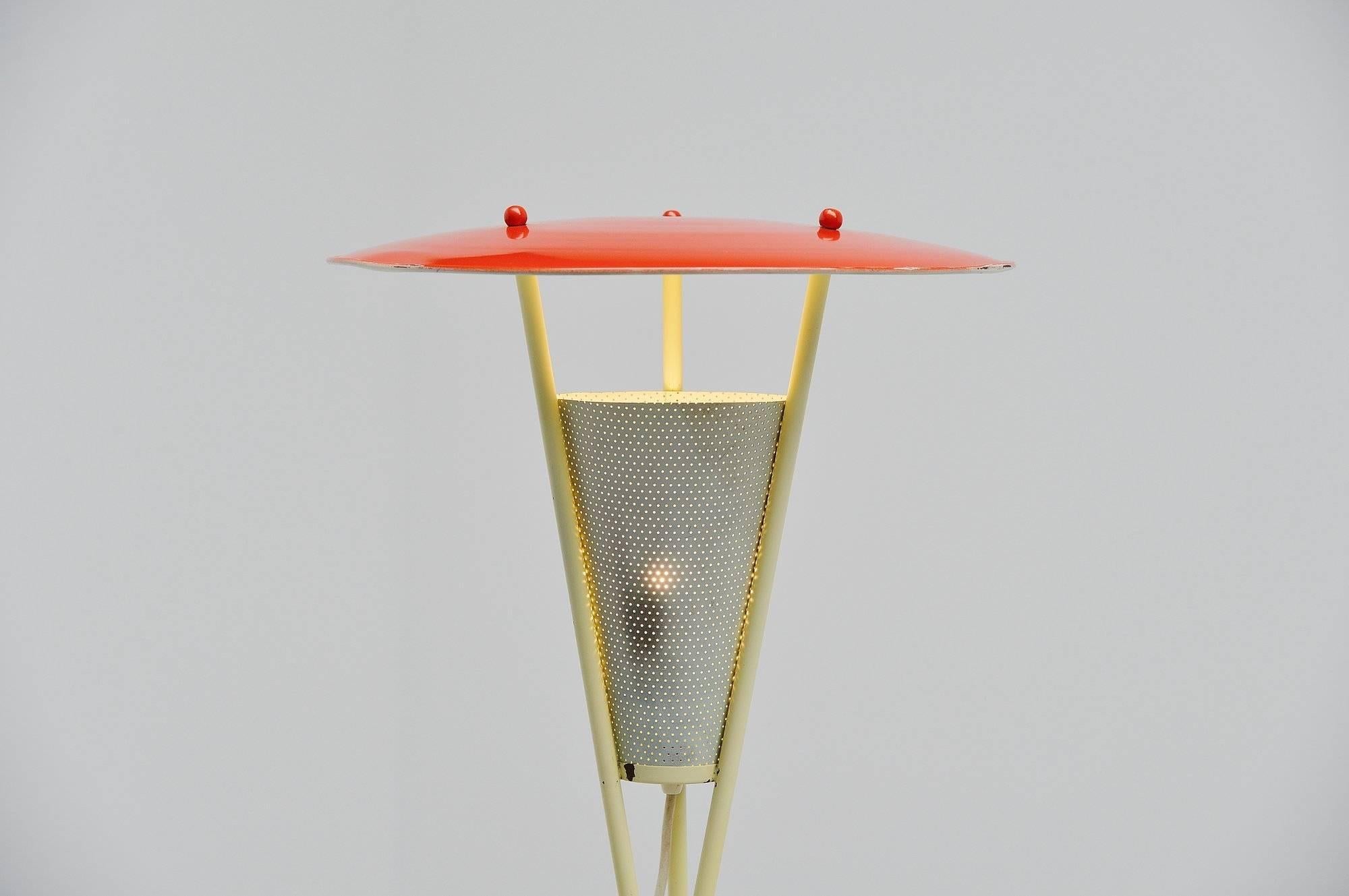 Très beau lampadaire tripode fabriqué par un fabricant ou un designer inconnu, Hollande, 1950. Cette lampe a une base tripode jaune, enveloppée l'une à l'autre par du plastique rouge. L'abat-jour est laqué rouge et l'abat-jour diffuseur découpé est
