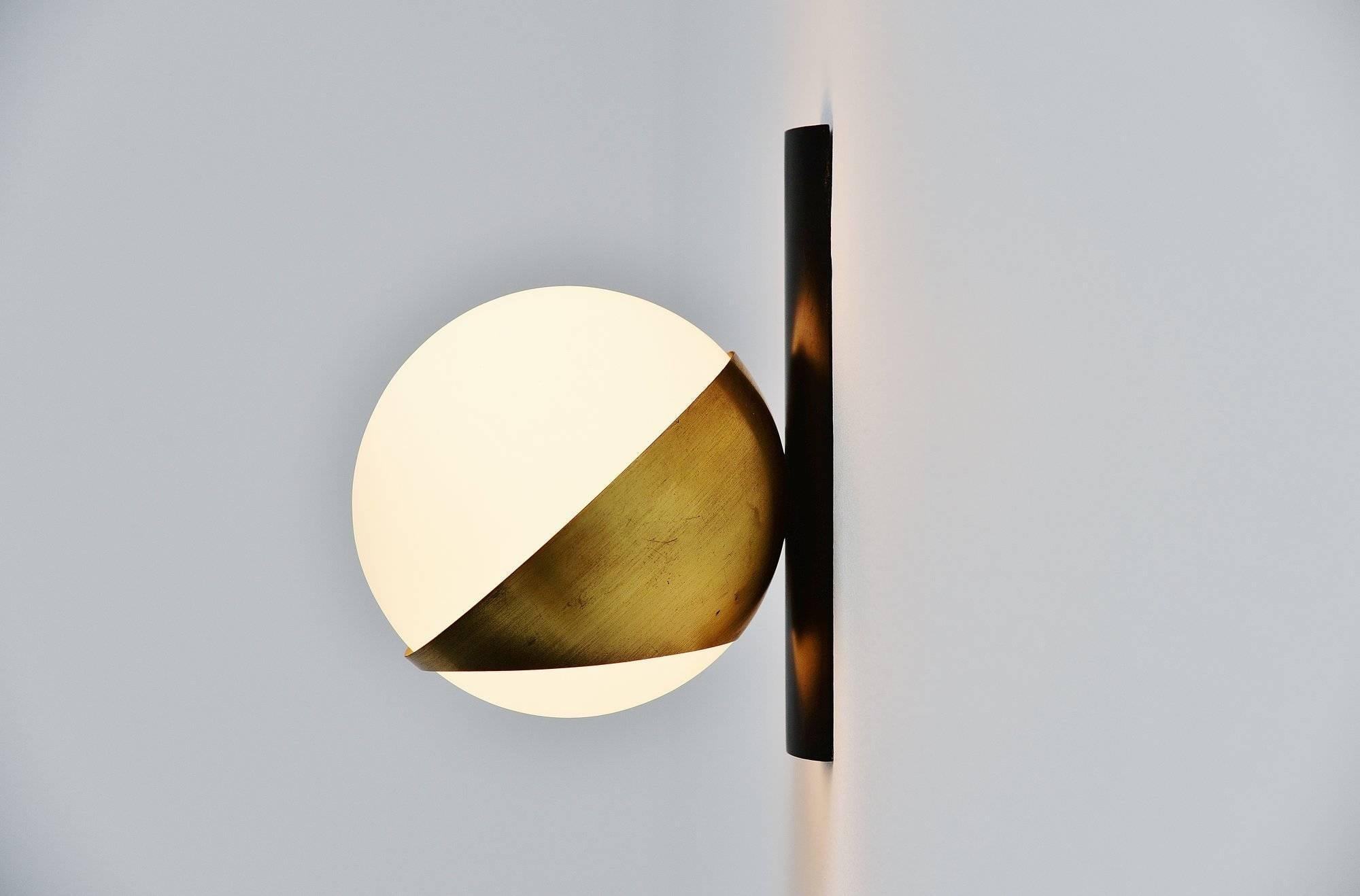 Nice modernist wall sconce designed and manufactured by Stilnovo, Italy, 1950. This lamp has a black wall plate and a brass sphere holder. The white frosted glass shade gives nice warm light when lit. The lamp is in good original condition with a