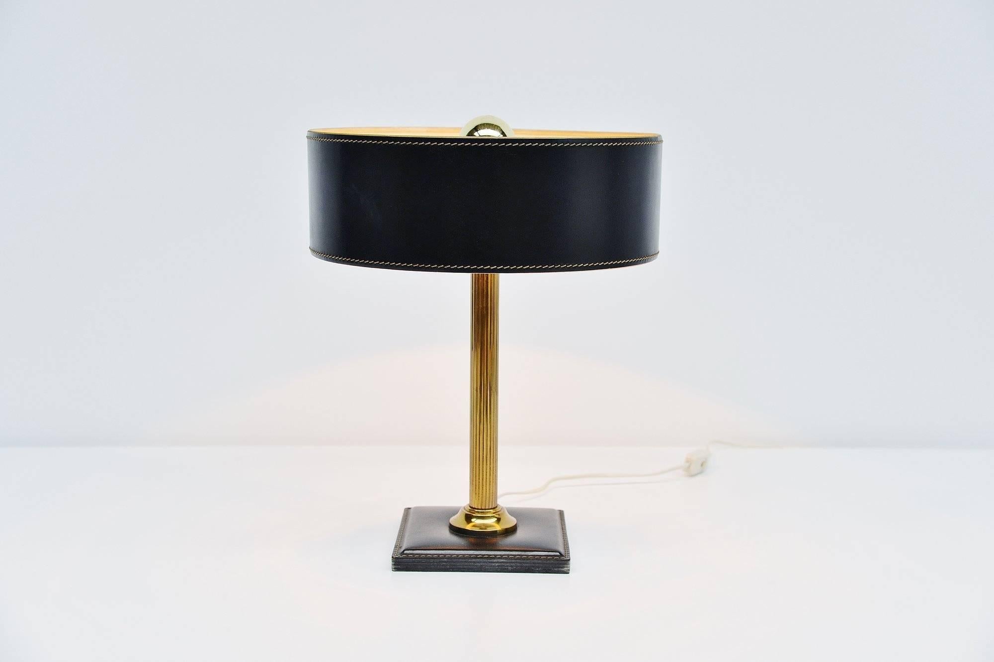 Very nice quality table lamp designed and manufactured by Jacques Adnet, France, 1960. This lamp has a square black leather base with a brass bar, the shade is also in black leather. Nicely stitched as all the works by Adnet are. The lamp gives very