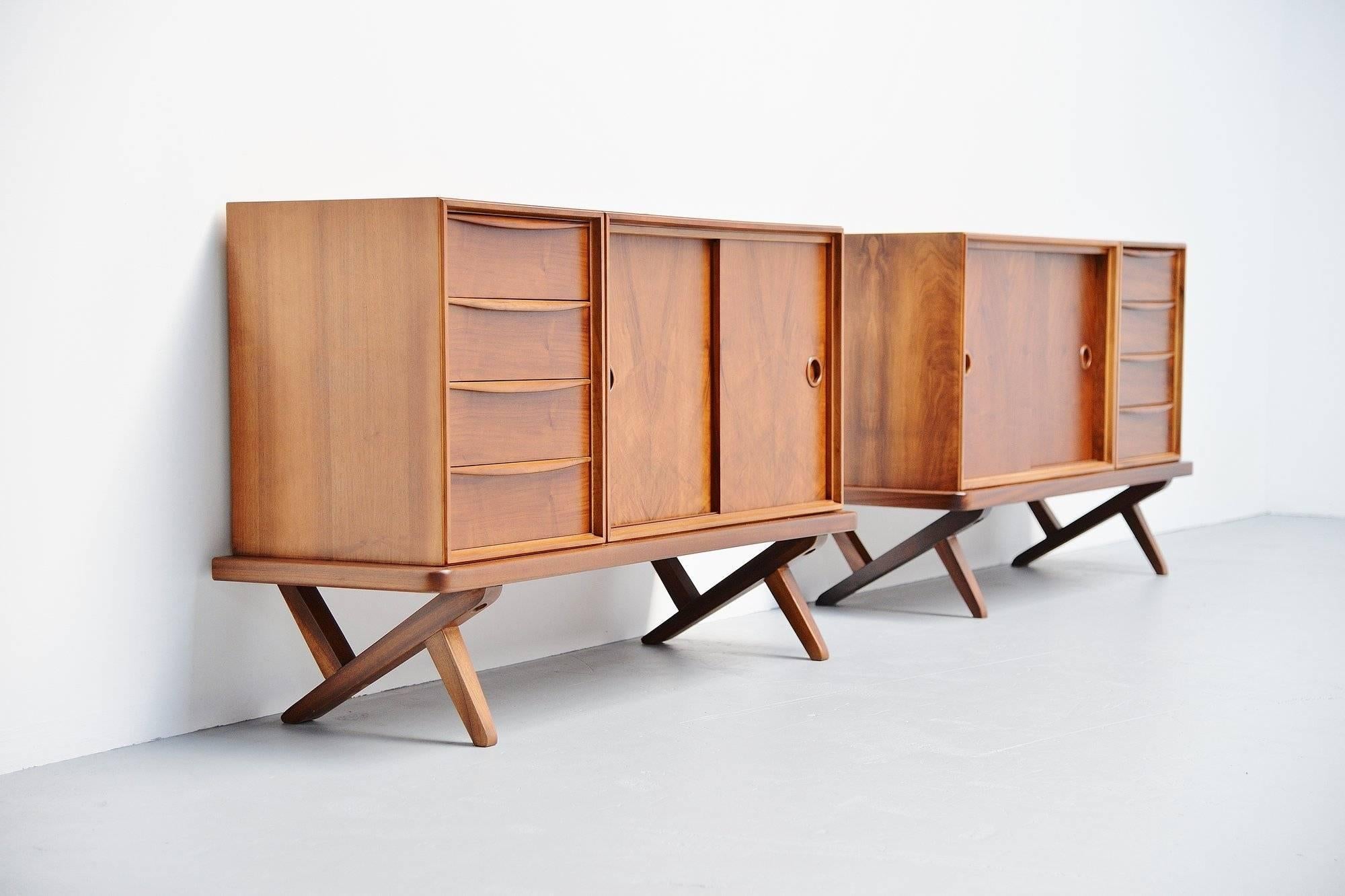 Nice pair of small credenzas designed by Rudolf Bernd Glatzel for Fristho Franeker, Holland 1955. These walnut credenzas have 4 drawers on the left and 2 sliding doors on the right with a shelve behind, or the opposite as this is a mirrored pair.
