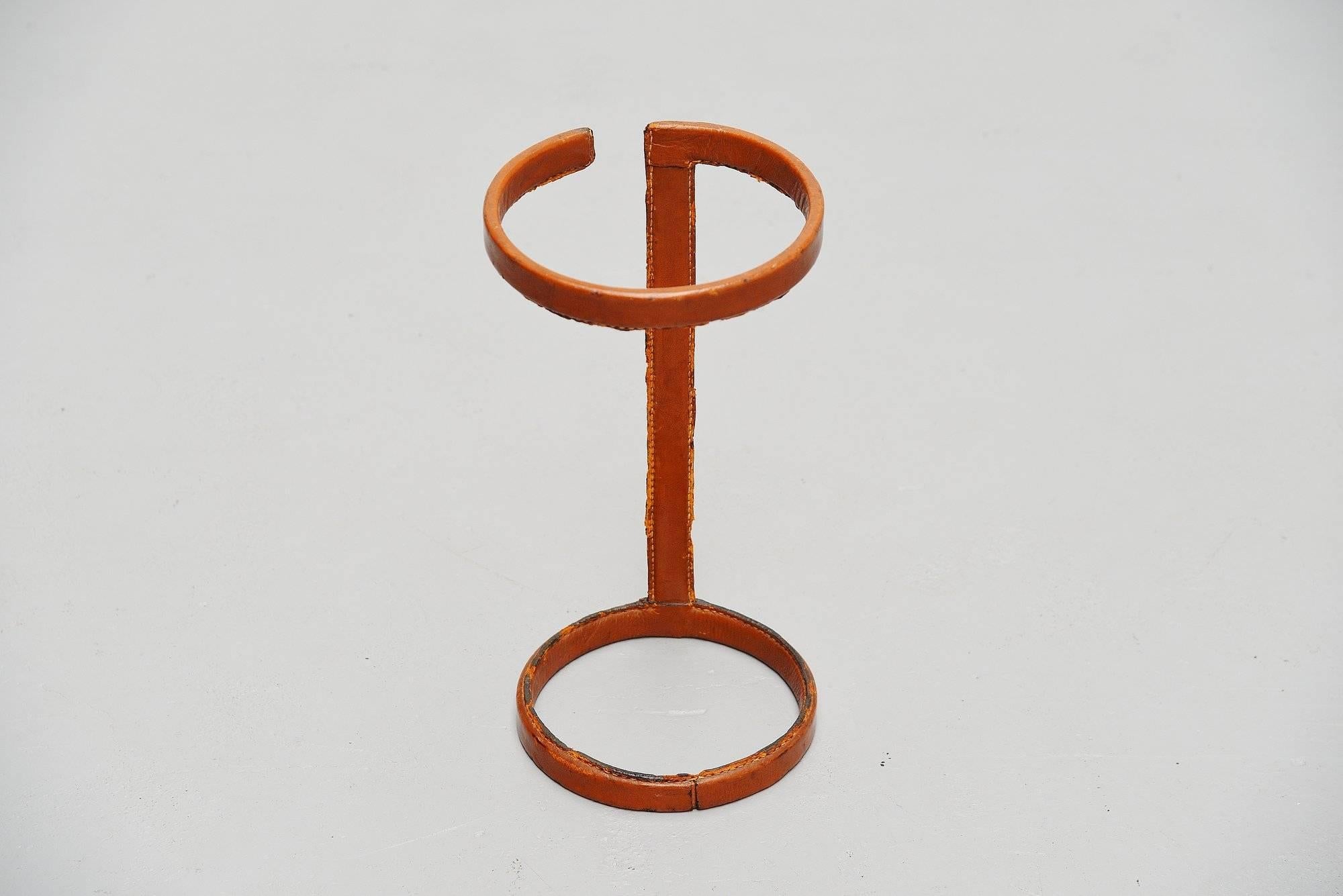 Decorative umbrella stand designed by Jacques Adnet and produced in the Atelier of Jacques Adnet, France, 1960. This umbrella stand has a cognac stitched leather frame with metal inside. It has some losses and a strong patina but it suits a piece