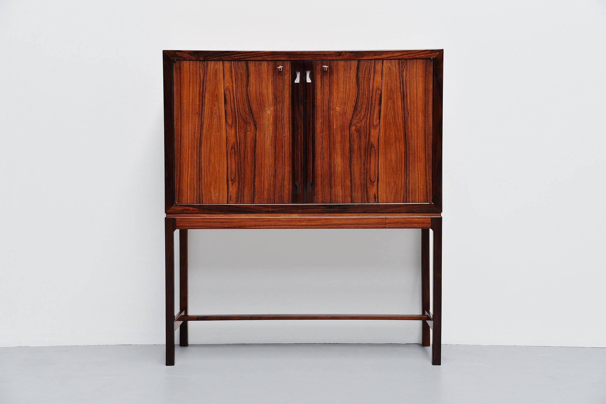 Highly refined dry bar cabinet in rosewood designed by Torbjorn Afdal, manufactured by Bruksbo Norway, 1960. This high quality dry bar is fantastically made and has a very nice inside with mirror, glass shelves, bottle holders and extractable tray