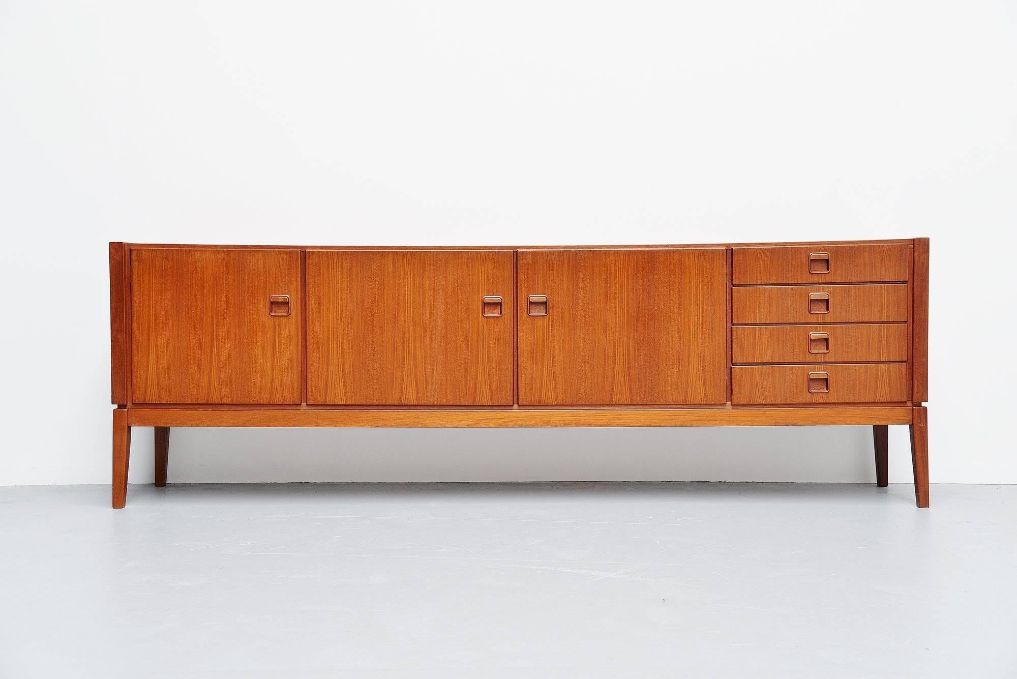 Nice teak wooden sideboard designed by Rudolf Bernd Glatzel and manufactured by Fristho Franeker, Holland, 1960. The sideboard has three folding doors with shelves behind on the left and on the right there are four drawers. The sideboard is in
