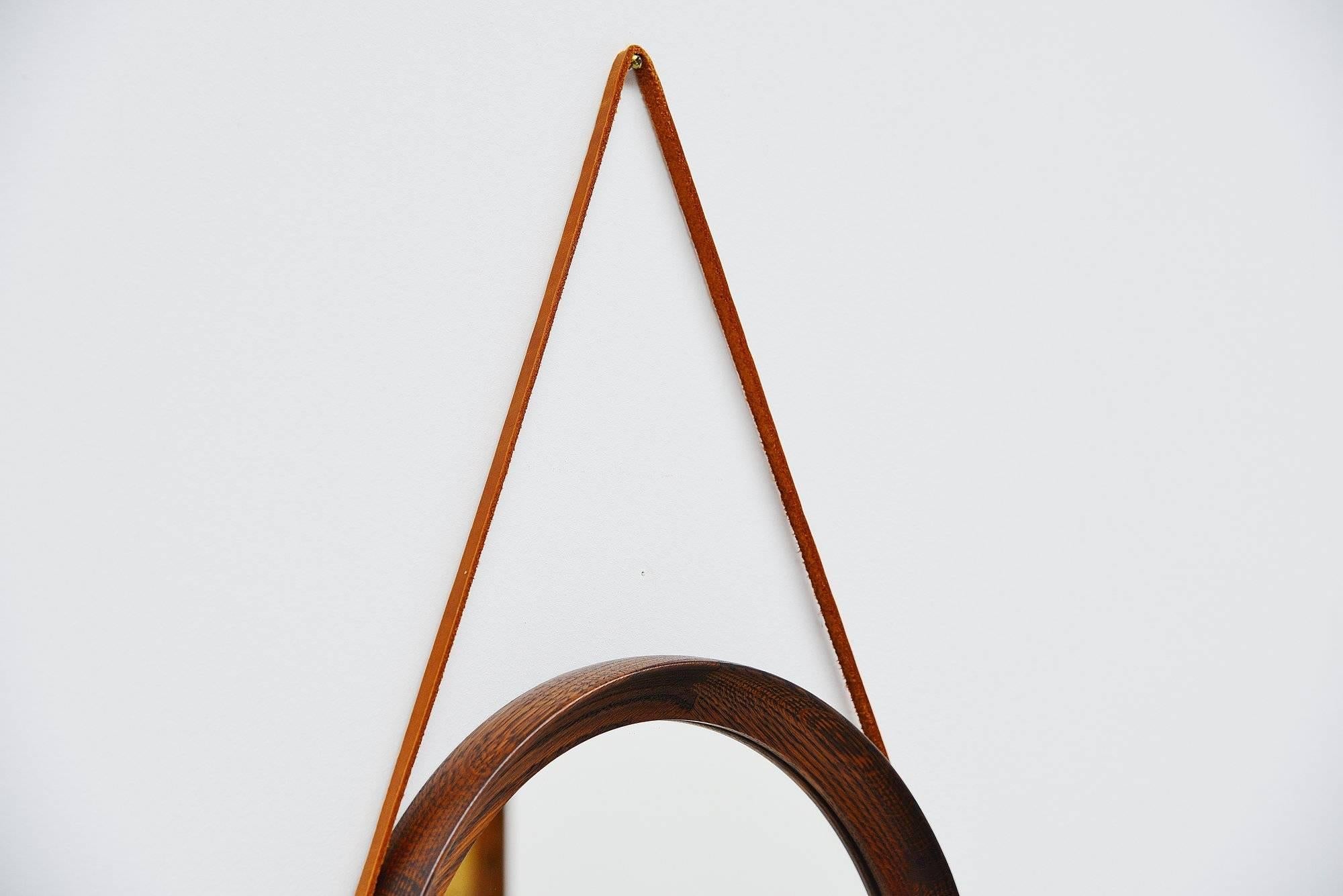 Very nicely made and crafted wall mirror designed by Uno and Osten Kristiansson, manufactured by Luxus, Sweden, 1960. This mirror was made of solid stained oak wooden parts with nice dovetail connections and a natural leather strap. The mirror is