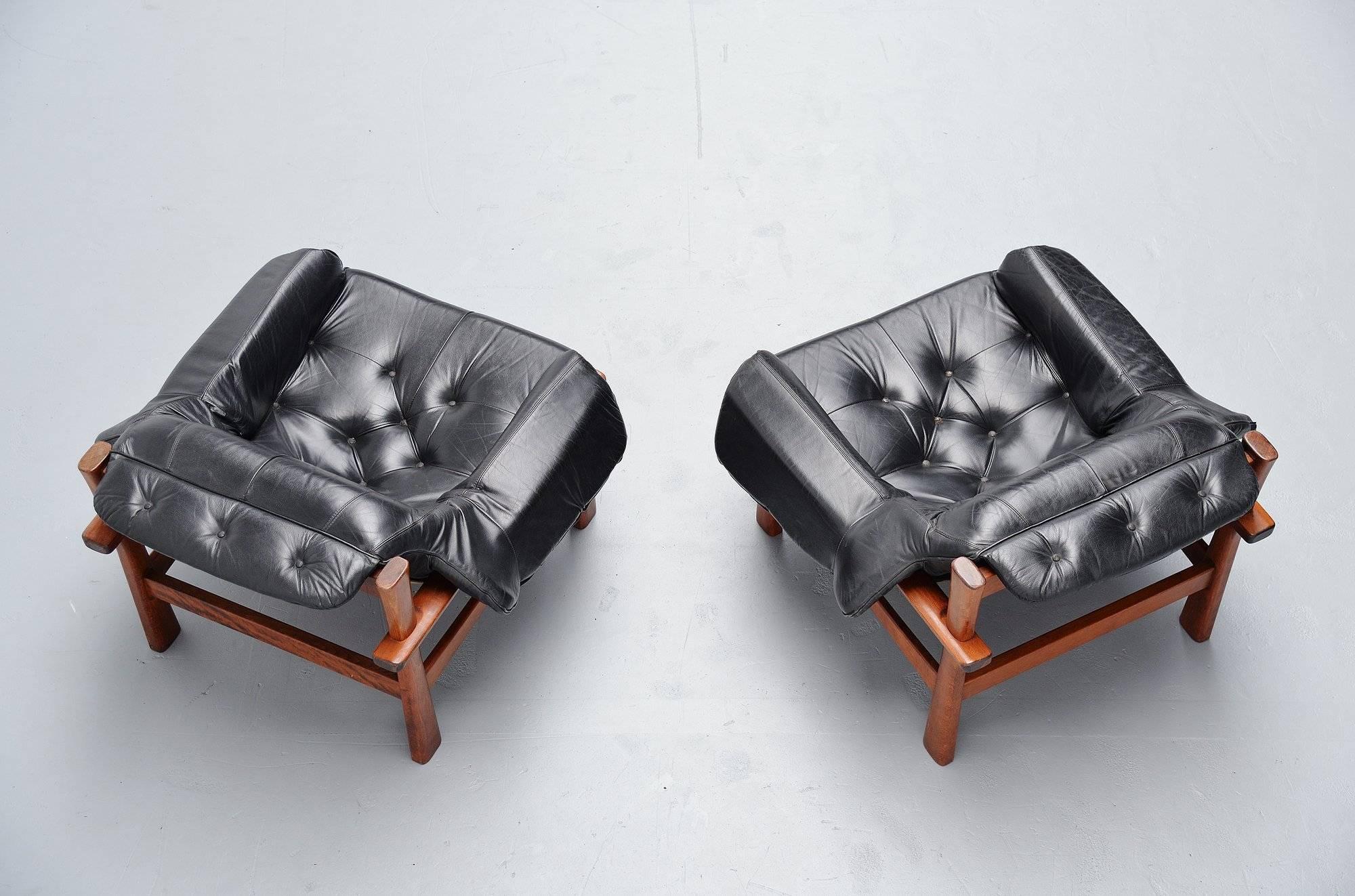 Nice looking pair of lounge chairs designd by Percival Lafer for Lafer MP, Brazil, 1960. These lounge chairs have a solid teak wooden frame and the black leather cushions rest on natural leather straps mounted with wooden knobs. Super nice set of