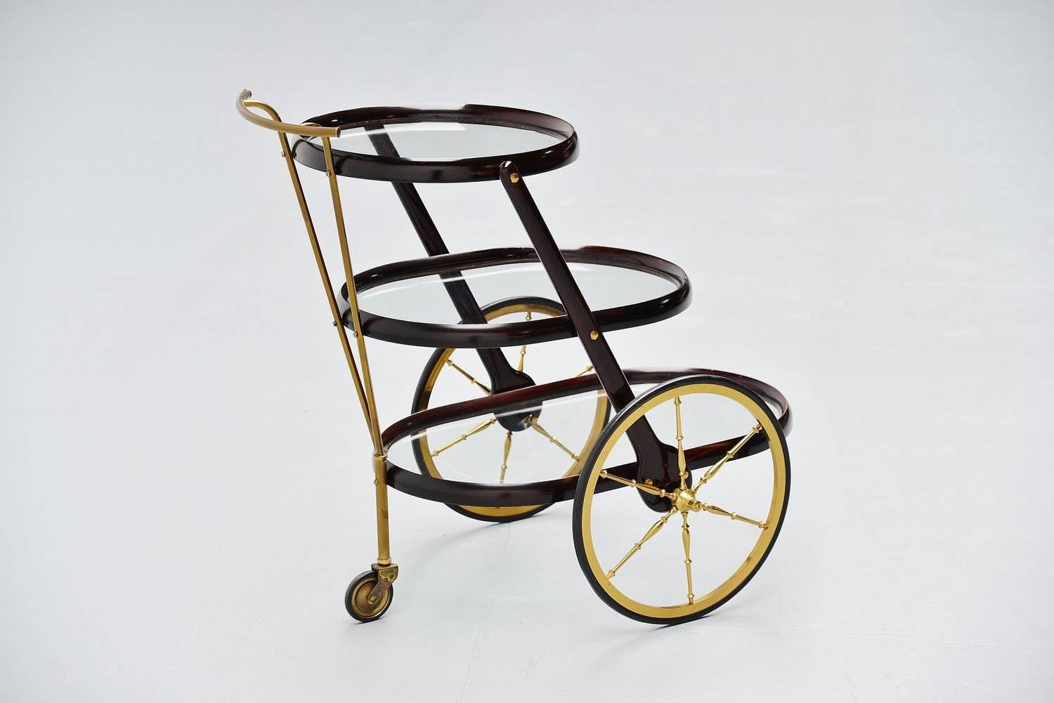 Fantastic shaped bar cart designed by Cesare Lacca, Italy 1950. Tri level bar cart made of stained mahogany wood and brass details. The cart has glass tops and is in very good original condotion. Wheels work perfectly too. Very nice typical Italian