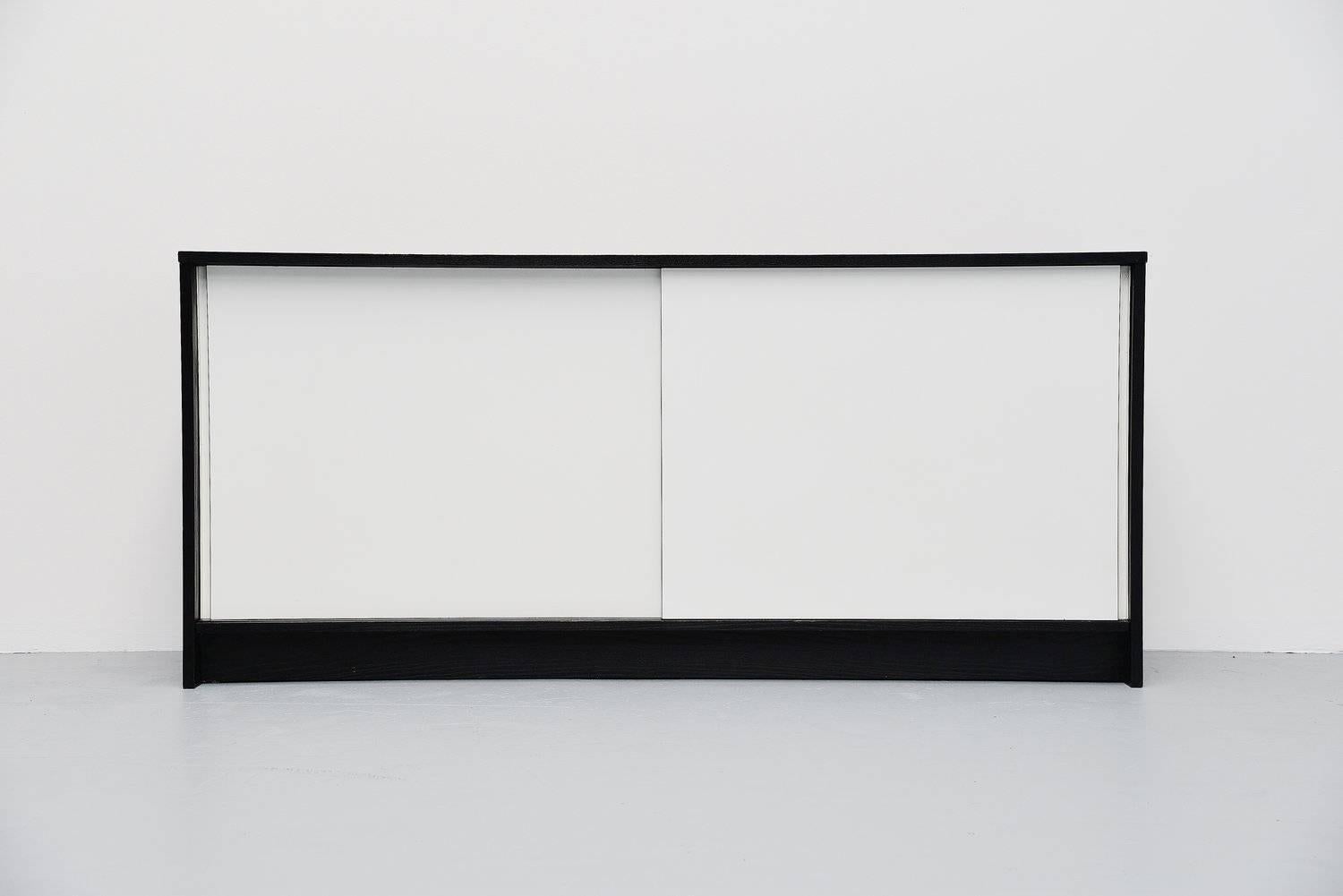Very nice credenza designed by Martin Visser for 't Spectrum, 1965. This credenza is model KW90 which is a bit higher than KW60. This has a black ebonized ash wooden casing and two white laminated sliding doors with shelves and a drawer behind. The