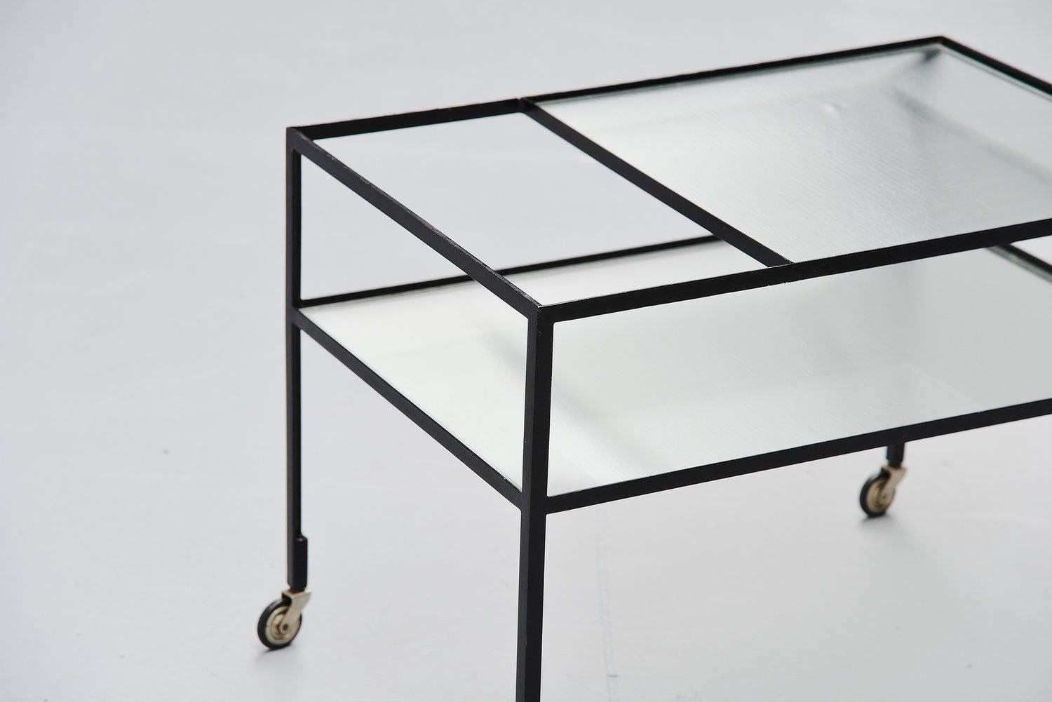 Very nice modernist bar cart designed by Herbert Hirche for Christian Holzäpfel KG, Germany 1956. This modernis shaped ta cart has a solid metal black lacquered frame in wheels, and it has 2 glass tops reinforced with metal wiring. Subtle serving