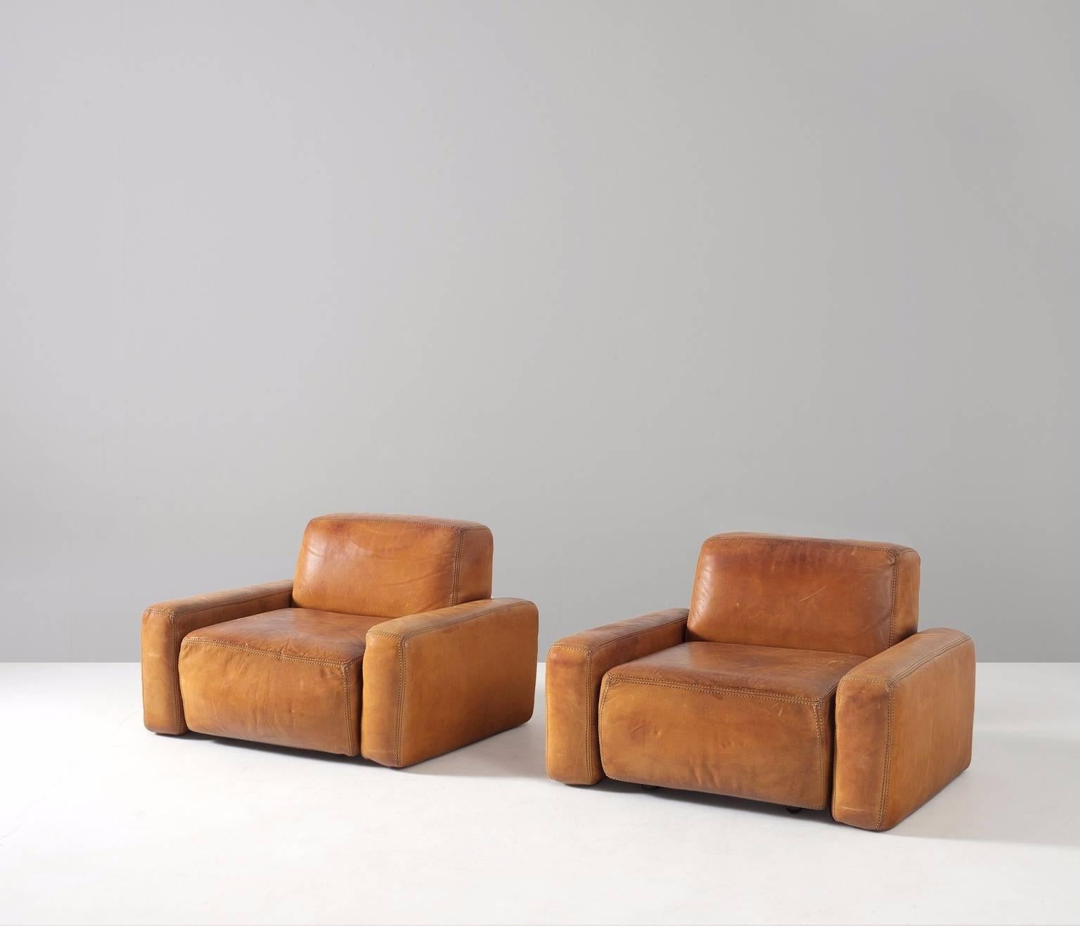 Pair of lounge chairs, in cognac leather, for Durlet furniture, Belgium, 1970s.  

Two wide cognac leather lounge chairs with a cubic and sturdy design. The patina on the natural leather is stunning. Different shades of brown create a beautiful
