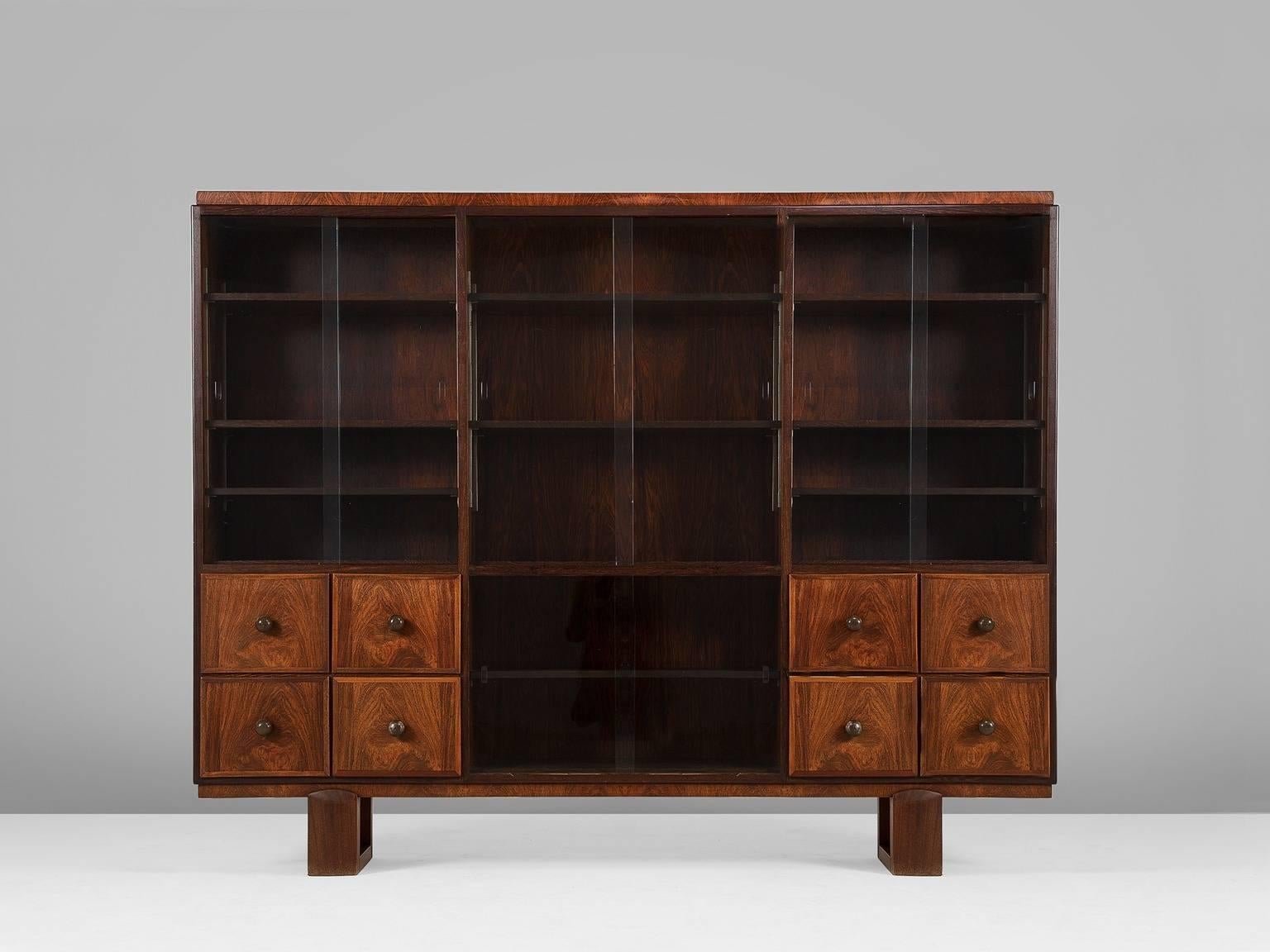 Cabinet, in wood and glass, France, 1960s. 

A very large French two-section display cabinet with adjustable shelving and glass doors. 8 large drawers on the bottom half, finished in beautiful wood. The rosewood shows a nice warm grain. The shelves
