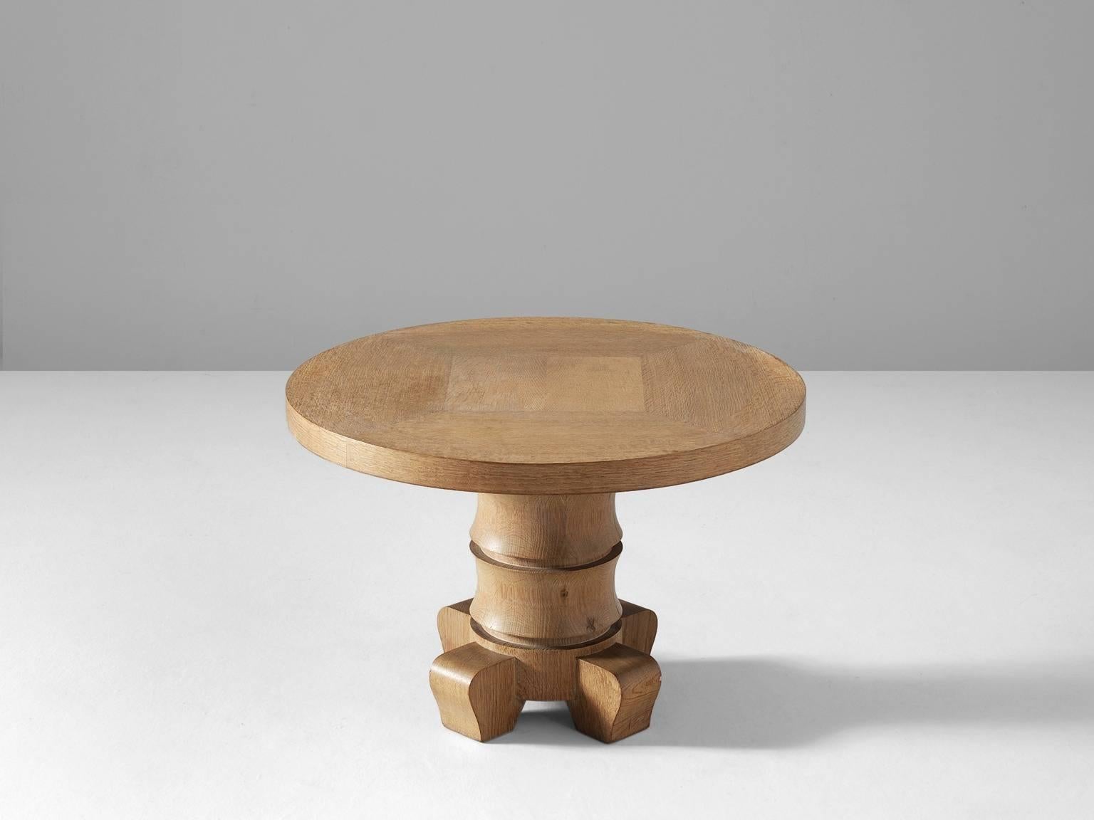 Coffee table, in oak, France, 1960s. 

Round coffee table in solid oak. The base consists of three rounded legs and one pillar. The round base consists of several rings, which reminds of a palm tree. Round top with wooden inlay of a square. Quite