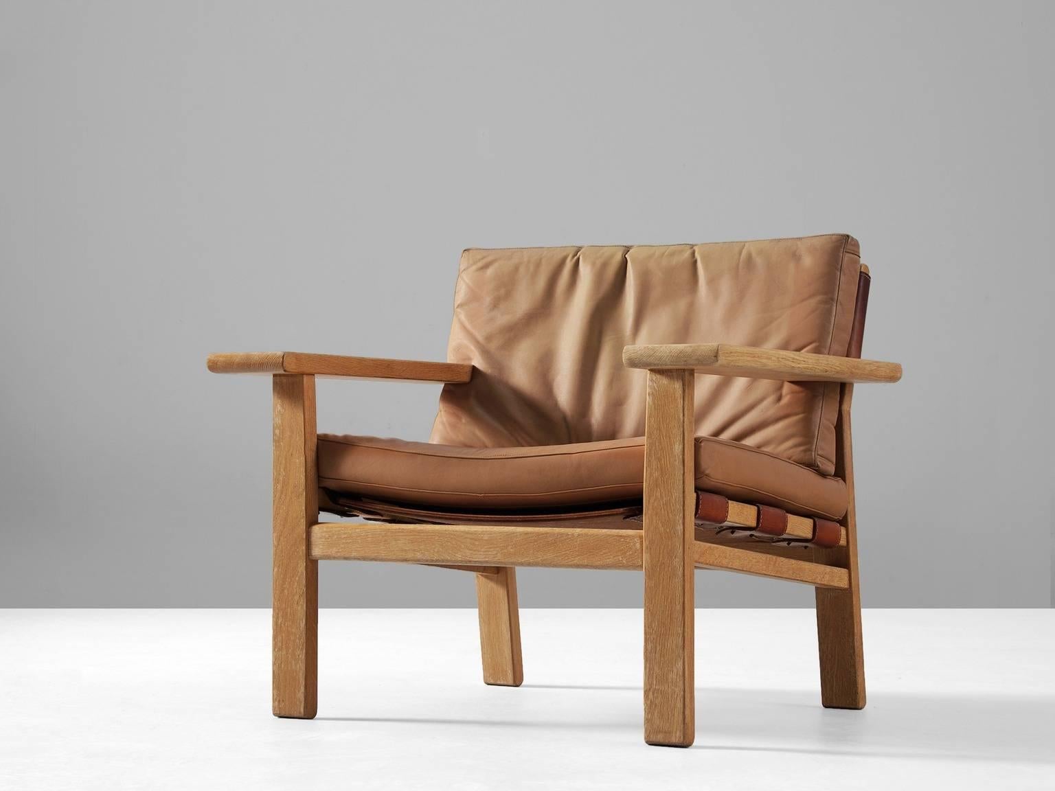 Armchair, in oak and leather, by Kurt Ostervig for K.P. Møbler, Denmark 1950s. 

Sturdy armchair in solid oak and saddle leather. This design of Ostervig has a strong resemblance to the Spanish chair of Børge Mogensen. Yet the design of this