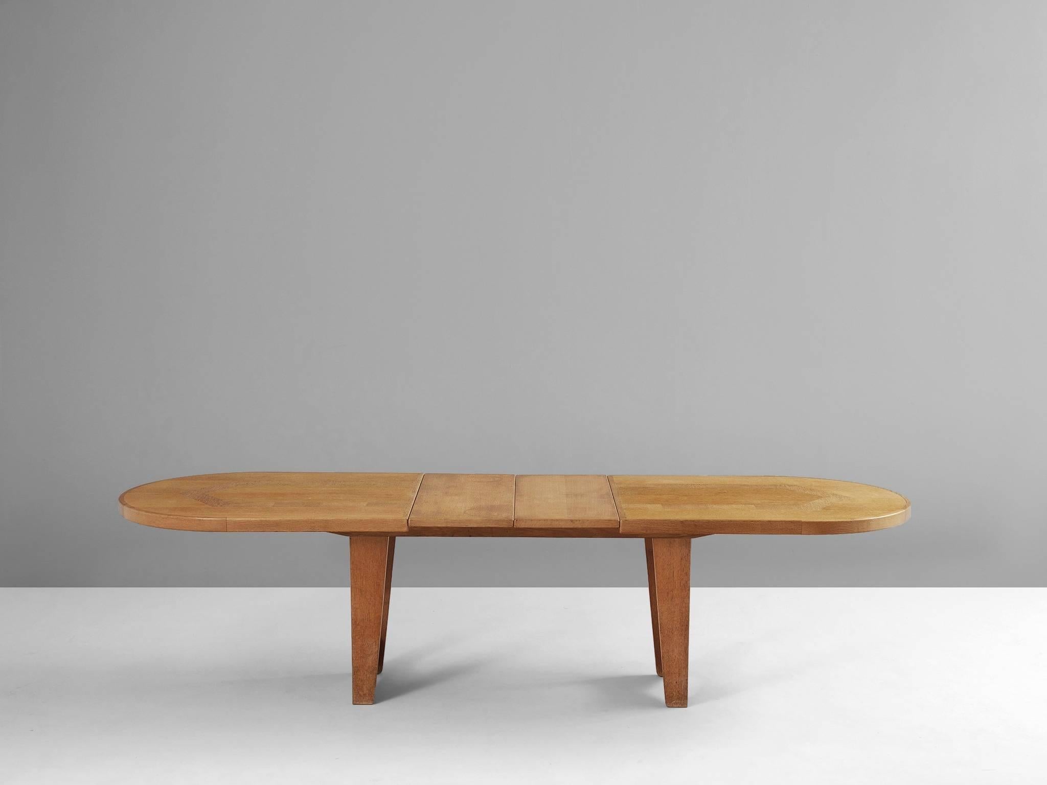 Extendable dining table, in solid oak, by Guillerme & Chambron, France, 1960s. 

Oval shaped dining table with inlaid top. This extendable table in solid oak comes with two optional leaves, which makes it a very versatile item. The two legged base