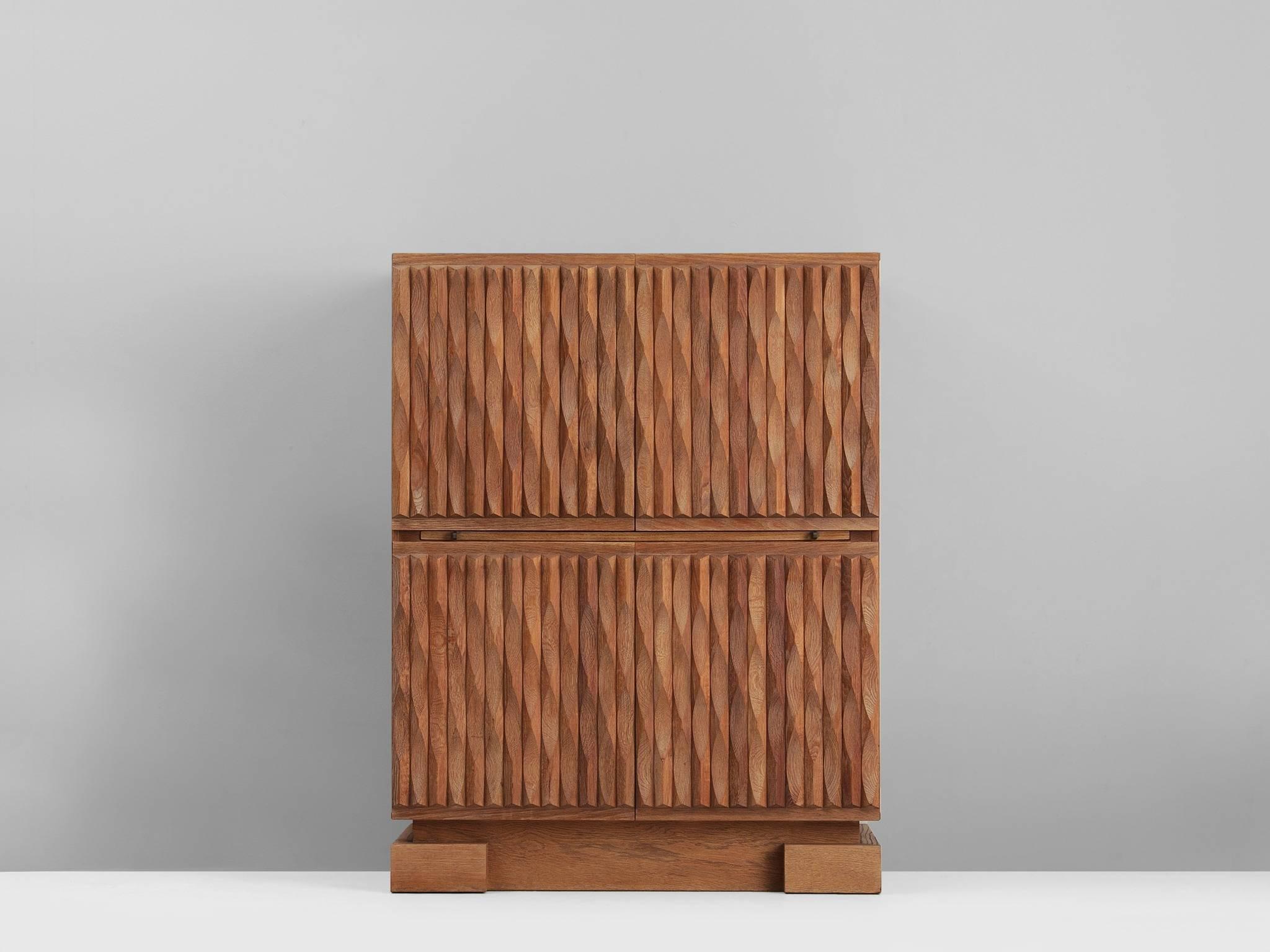 Brutalist credenza, in oak European, 1970s. 

Sturdy high-board in oak with graphical designed door panels. Four door panels, each with a exceptional three-dimensional pattern. The continuous pattern gives this bar-cabinet a very strong