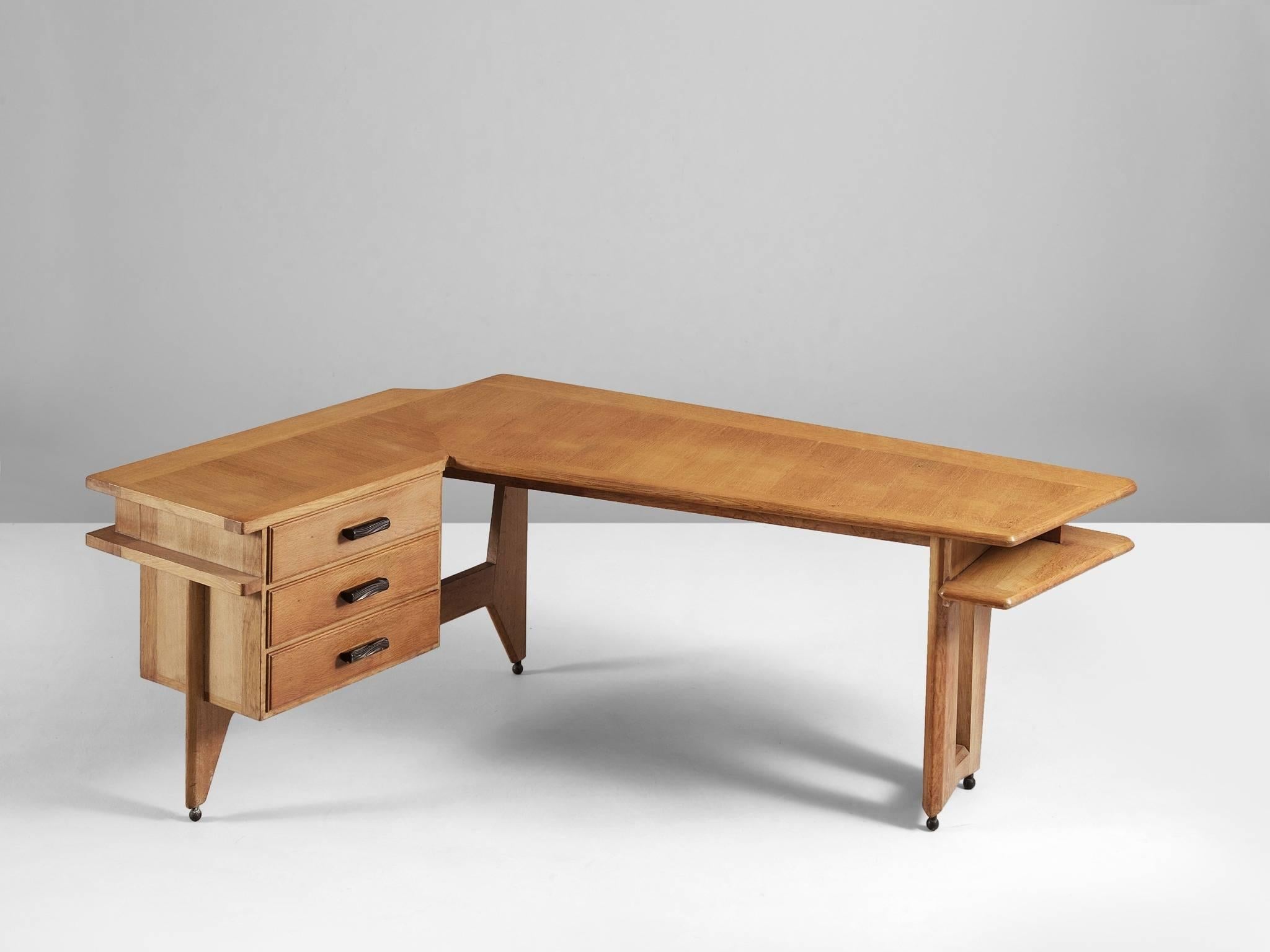 Desk, in oak, by Guillerme & Chambron, France, 1960s.

Desk & return in solid oak by French designers Guillerme et Chambron. This elegant corner desk shows interesting details. First there is the shaped of the top, which is L-shaped. There is