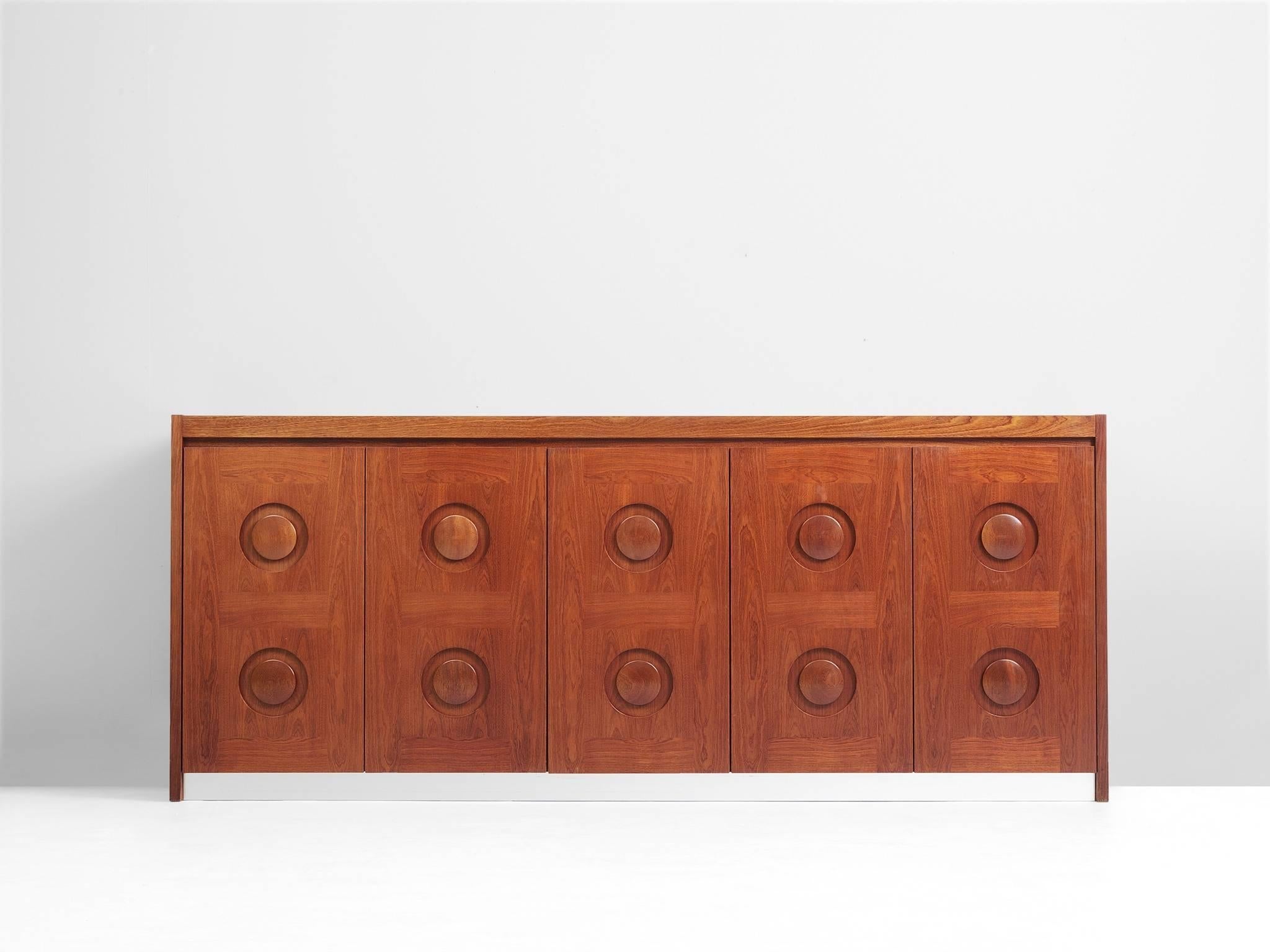 Brown Brutalist credenza in mahogany and aluminum, European, 1970s. 

Sturdy credenza in mahogany with graphical designed door panels. Five-door panels, each with a three-dimensional pattern of circles horizontal lines, which gives the cabinet a