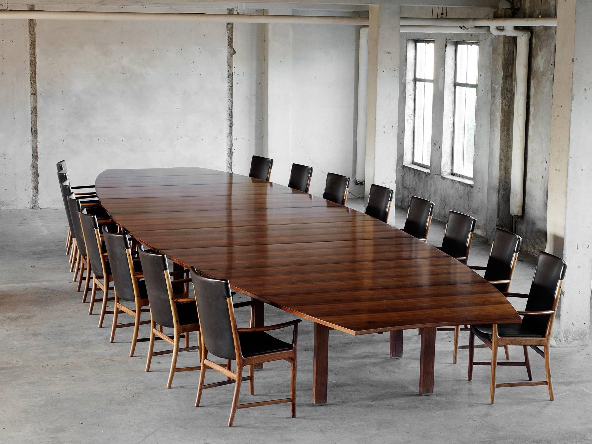 Conference table, in rosewood, by A.J. Iversen, Denmark, 1950s. 

Extremely large rosewood conference table. This 762 centimeters long table has a boat shaped top supported by 12 cubic legs. The exceptional large top consist of nine leaves. In