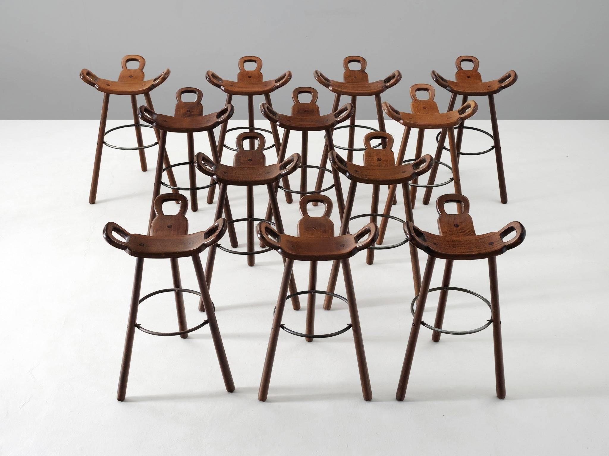 Set of 12 'Brutalist' or 'Marbella' bar stools, in stained beech and metal, Spain, 1970s. 

Large set of brutalist bar stools in dark-brown stained beech. The eye-catching part is the seating. A curved T-shape with three handles. The handles are