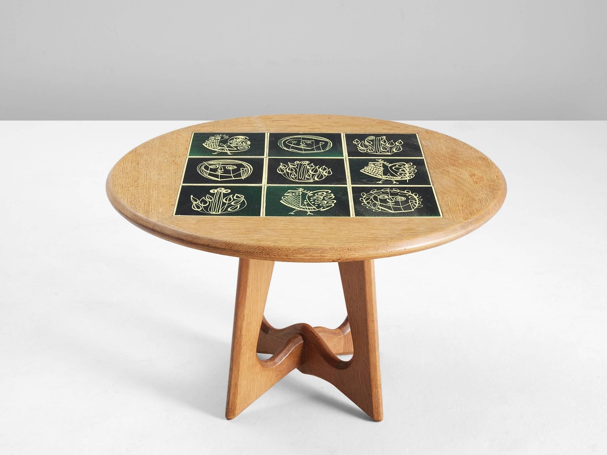 Coffee table, in oak and ceramic by Guillerme et Chambron, France 1960. 

Round oak coffee table with beautiful colored ceramic tiles in the top. The materials and forms of this table show the characteristics of the French designers Guillerme et
