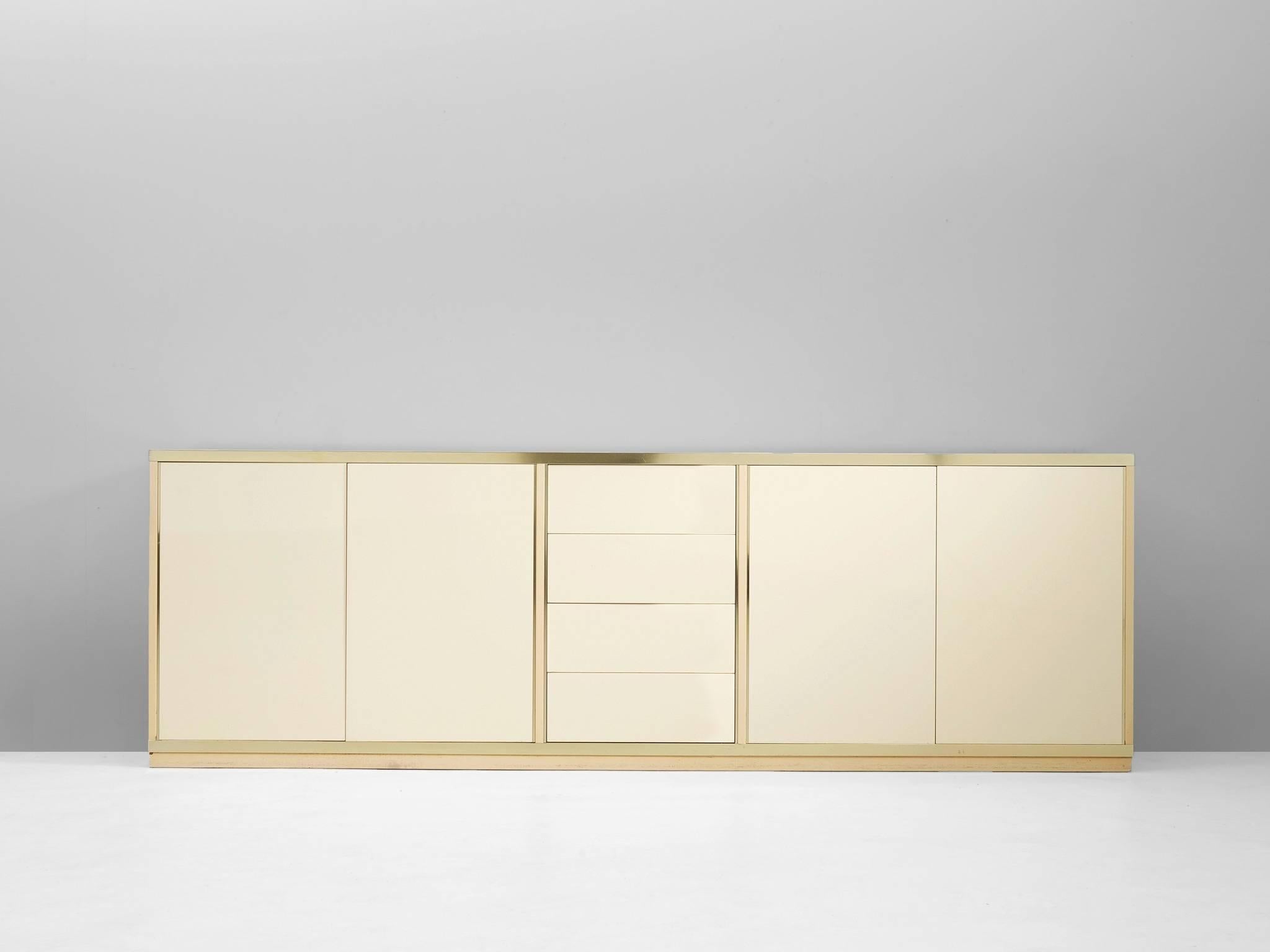 Sideboard, in lacquered wood and brass, Italy 1970s. 

High gloss sideboard in white, with brass frame. This credenza contains four doors with shelves and one compartment with four drawers. So this luxurious cabinet provides plenty of