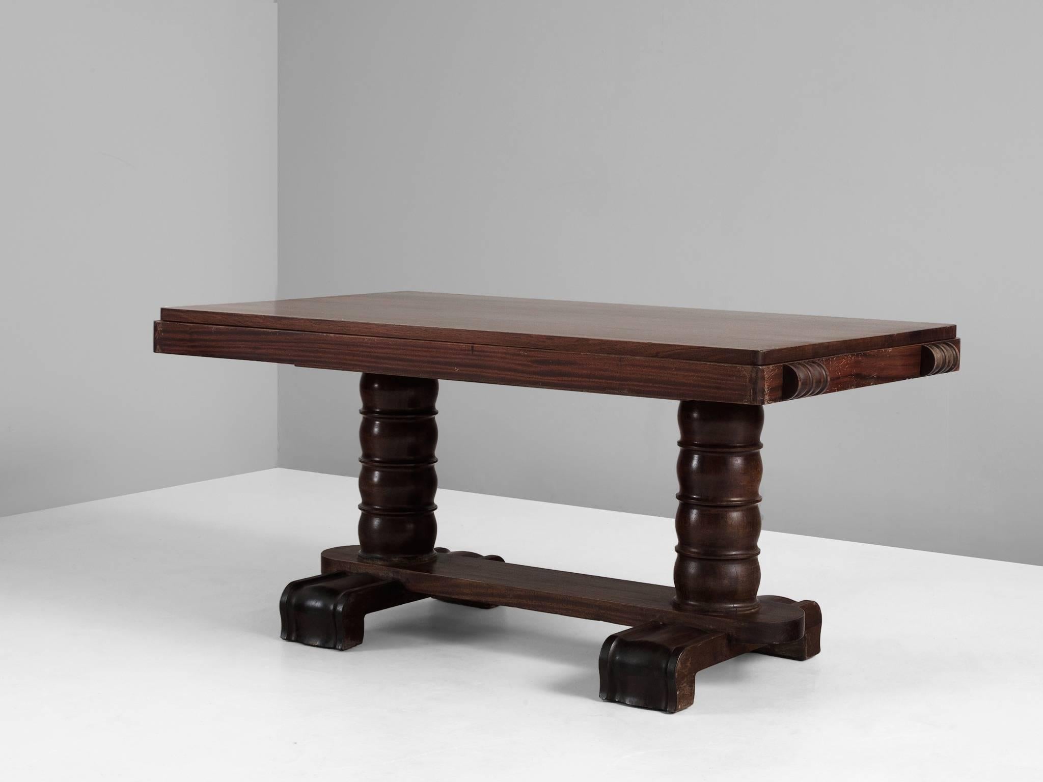Dining table, in mahogany by Gaston Poisson, France, 1940s. 

Majestic center table in dark brown mahogany. This Art-Deco table shows the great craftsmanship of Gaston Poisson. The base and legs are beautifully detailed with carving and woodwork.
