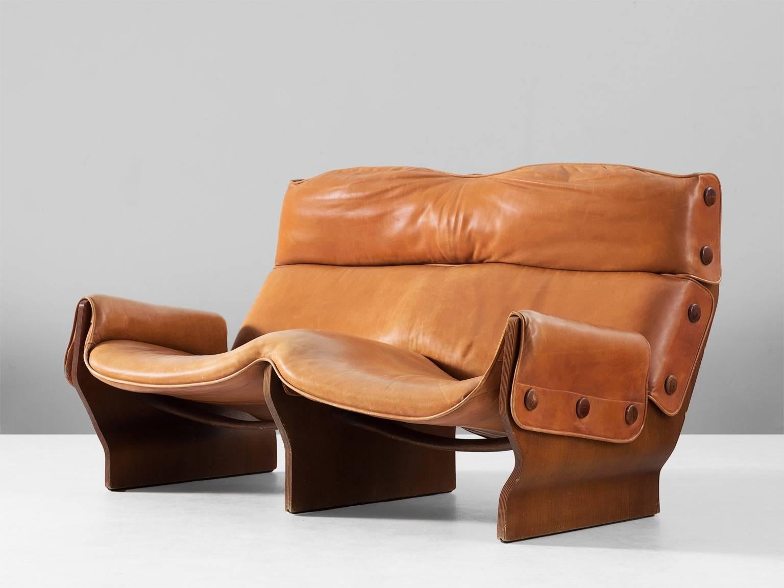 Settee 'Canada', in plywood and leather, by Osvaldo Borsani for Tecno, Italy, 1960s.

The 'Canada' sofa is composed of two sides made of moulded plywood connected by two contoured solid wood crosspieces performed in teak. Upholstered in original