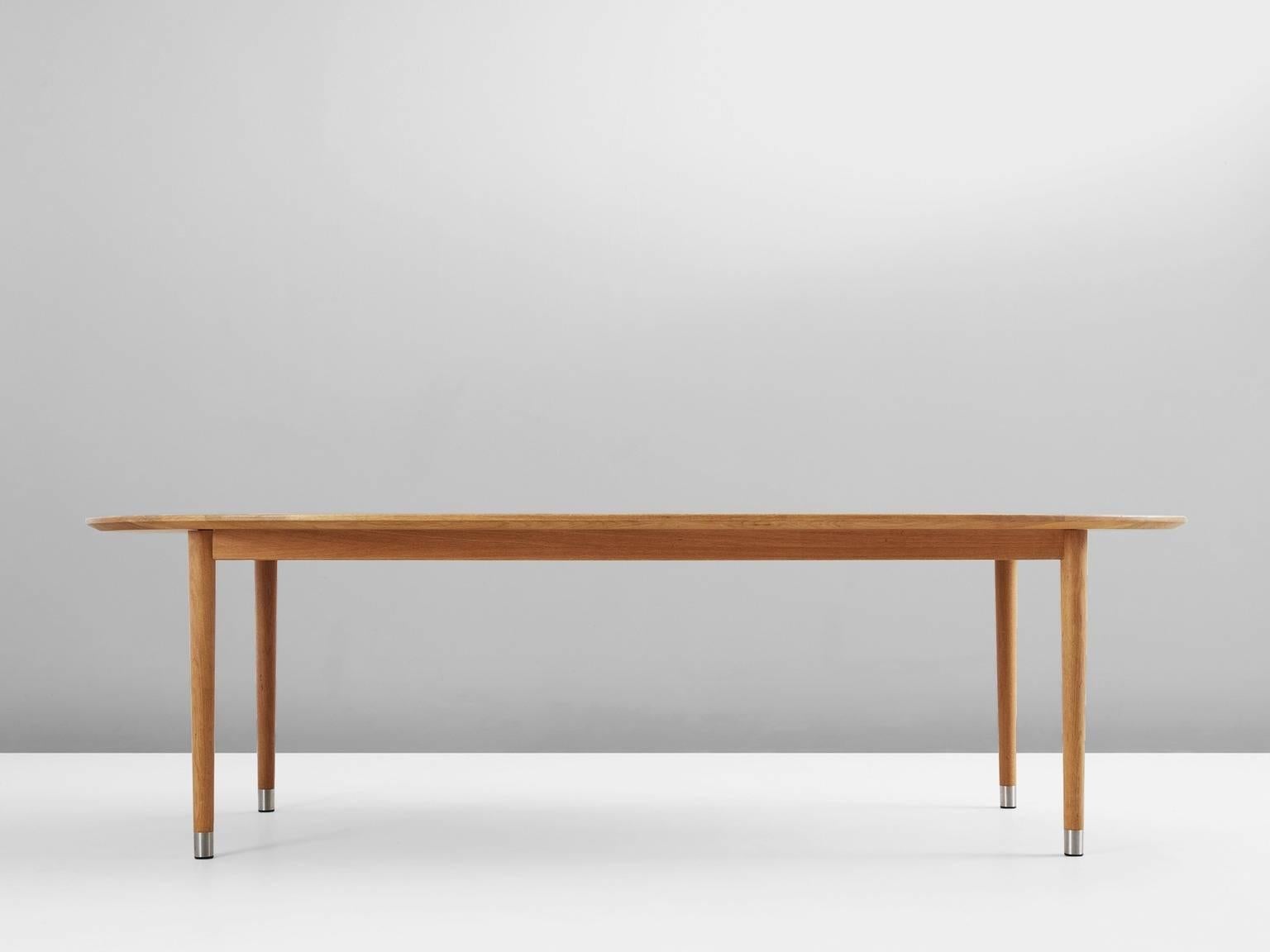 Dining table, in oak and metal, Scandinavia, 1970s.

Large oval dining table in oak. This table has a simplistic design. Due the cylindrical legs and oval shaped top, this design gets more elegance. The metal 'socks' in silver color on the table's